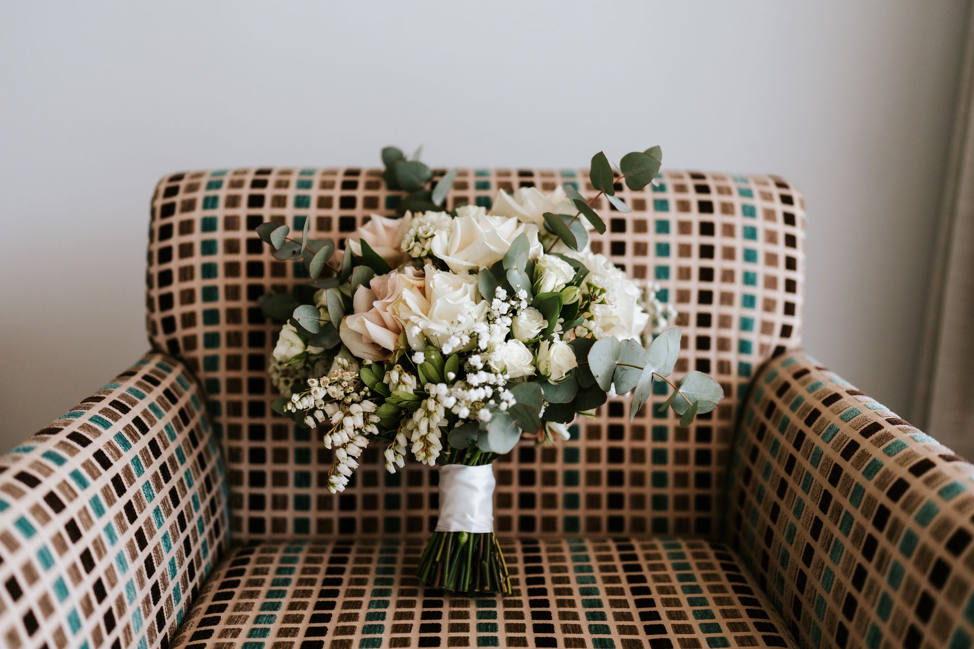 Bouquet of white and pink flowers on a patterned armchair