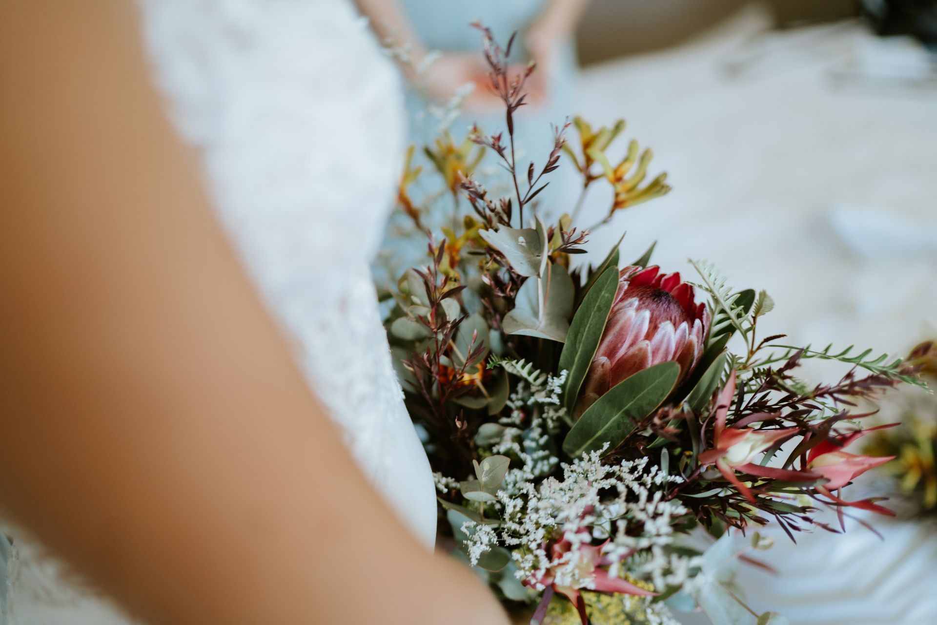 Wedding bouquet of red and white flowers beside a person in a white dress