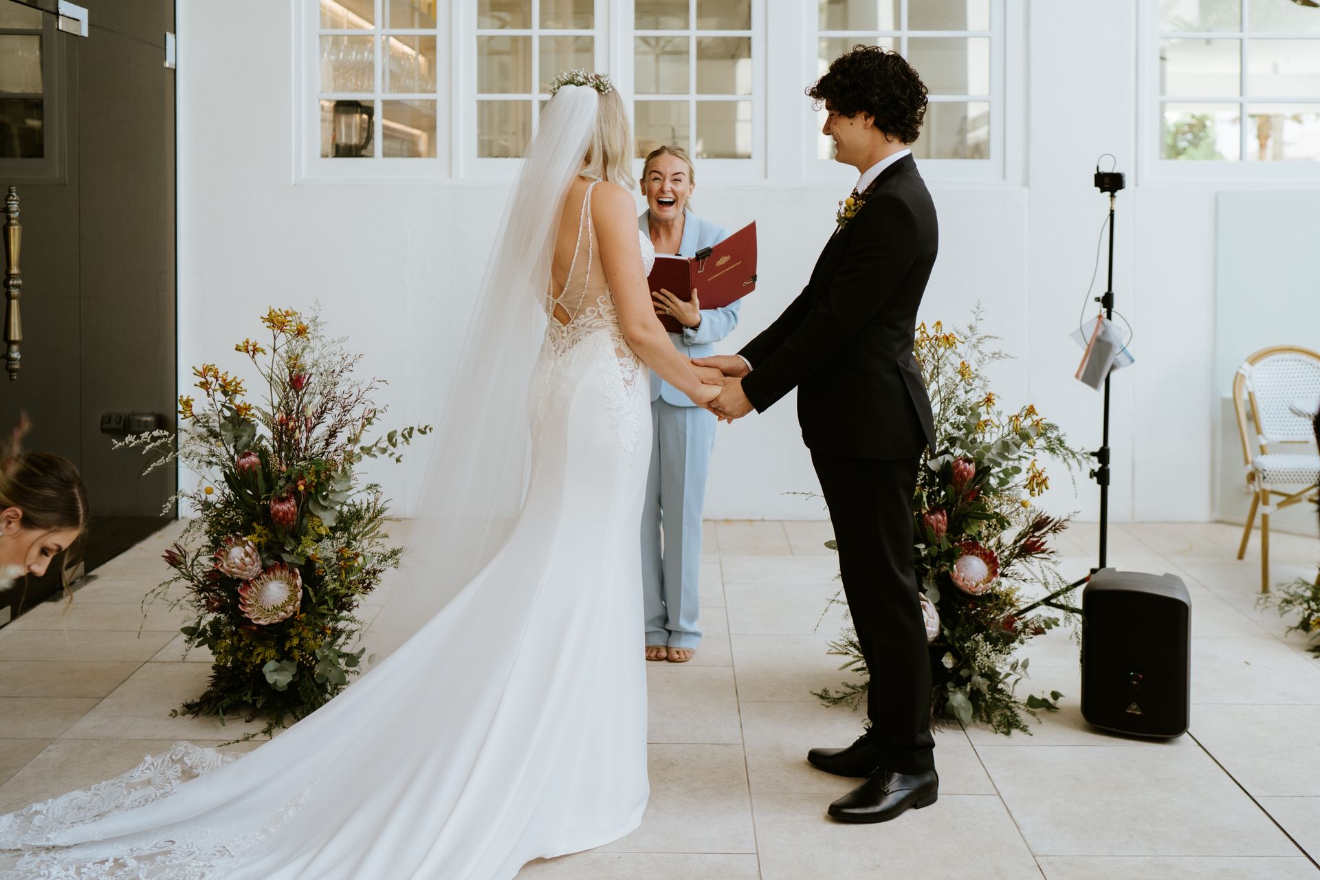 Bride and groom holding hands during an outdoor wedding ceremony in a bright courtyard