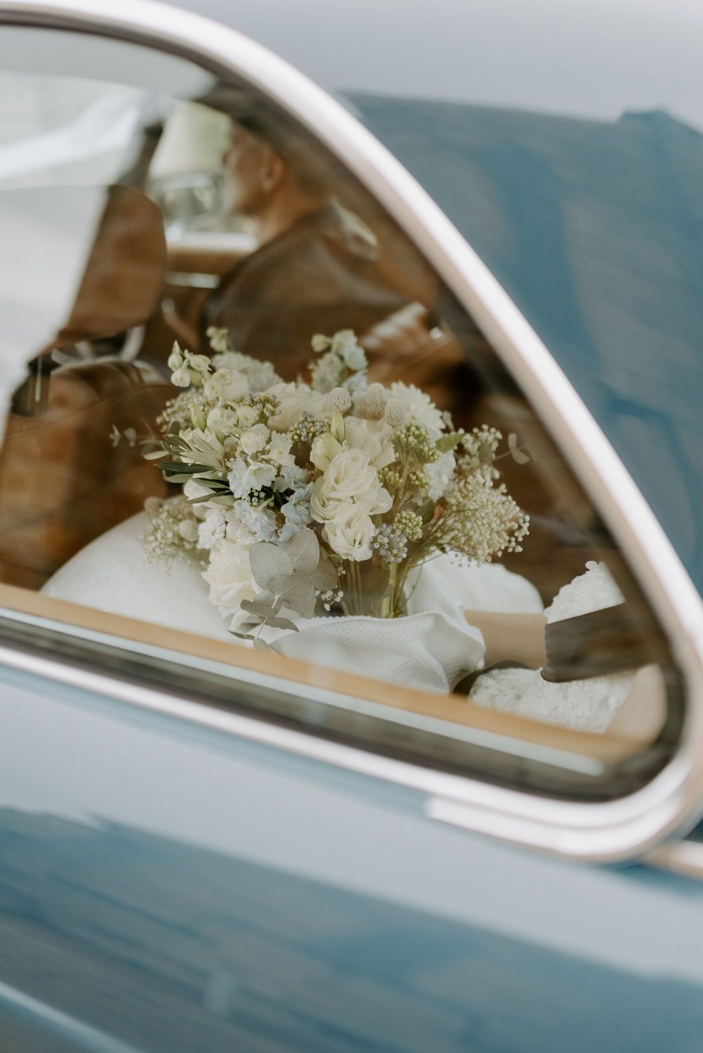 Bouquet of white flowers on a car seat seen through the rear window