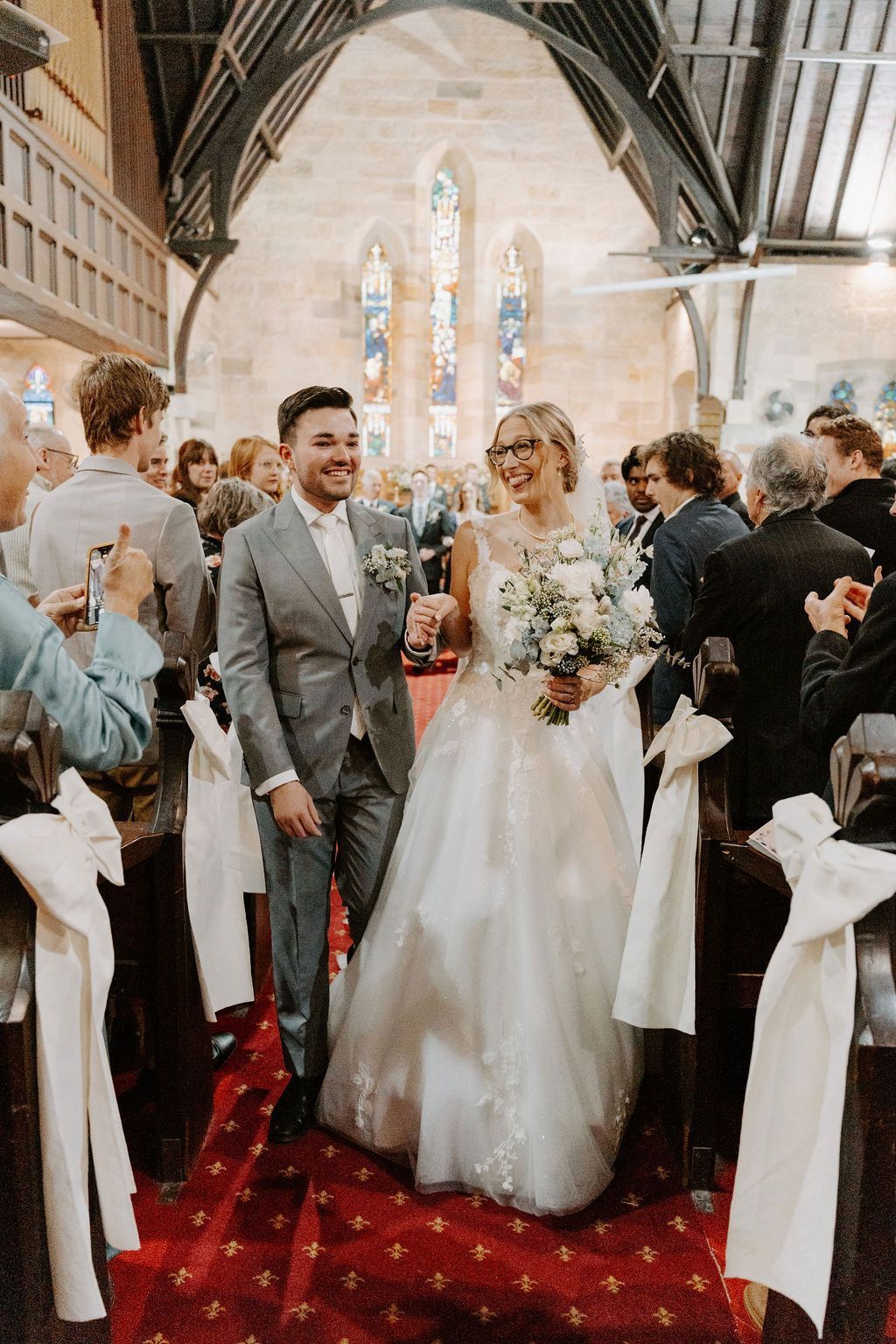 Wedding couple walking down the aisle in a church, surrounded by guests and white chairs