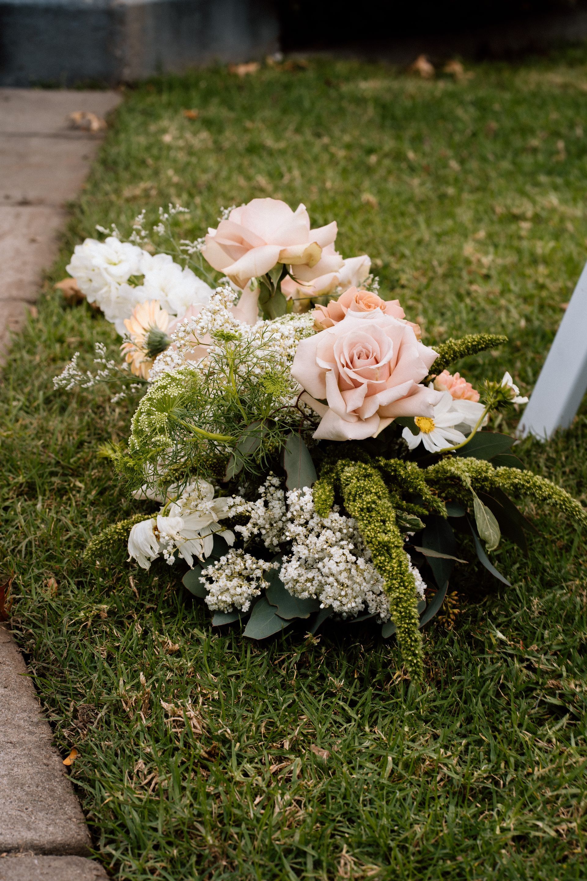 Floral arrangement with pale pink and white flowers on the grass outdoors