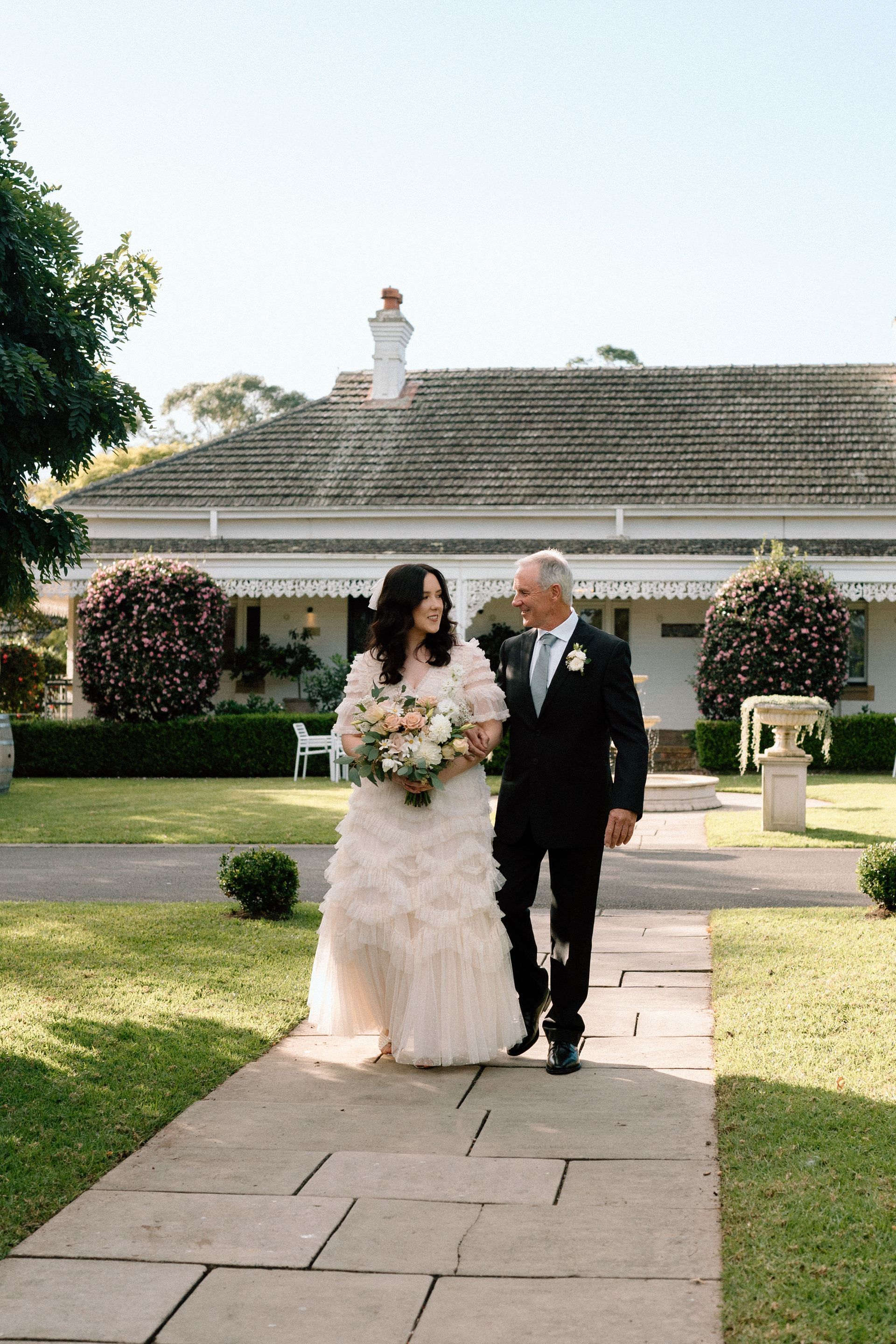 Bride and groom walking hand in hand on a stone path in a garden wedding setting