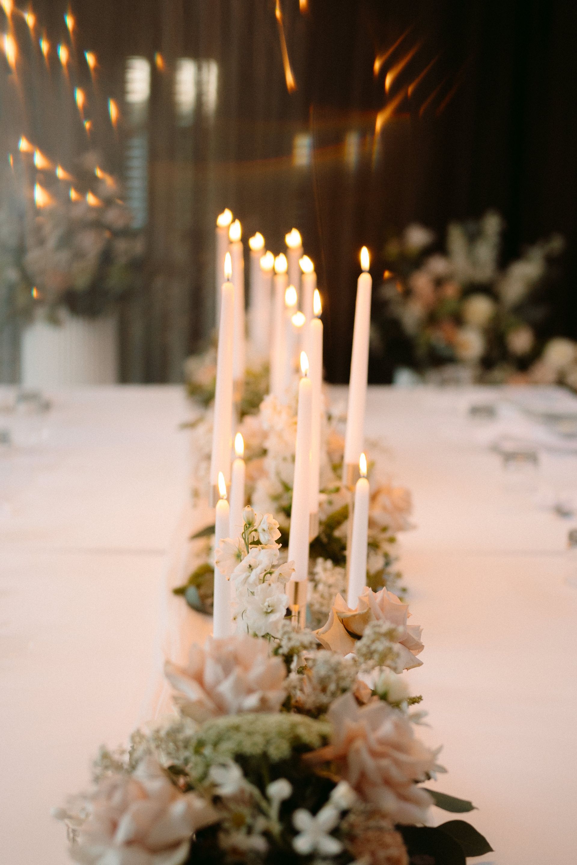 Elegant candlelit table centerpiece with white flowers on a long dining table