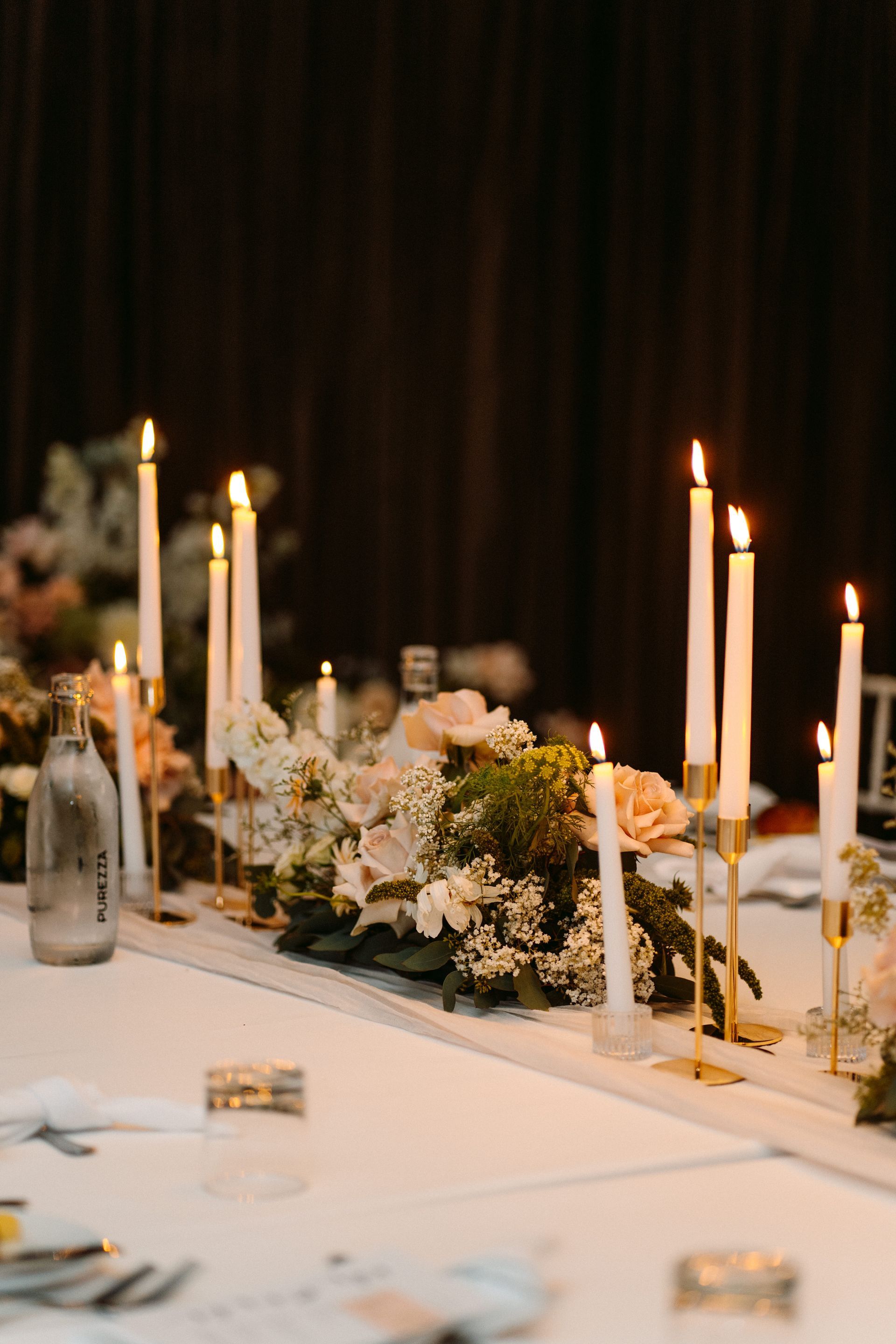 Elegant candlelit banquet table with white floral centerpieces and gold accents