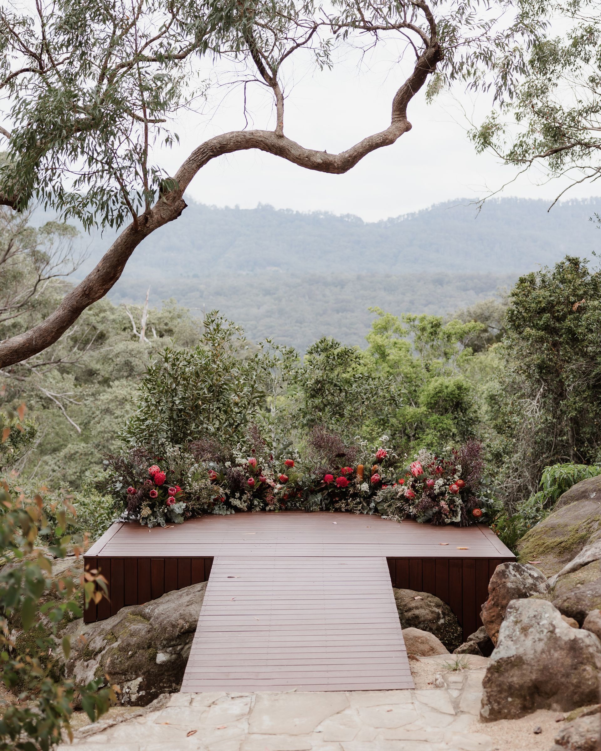 Wooden platform with floral decorations overlooking a misty forest view.