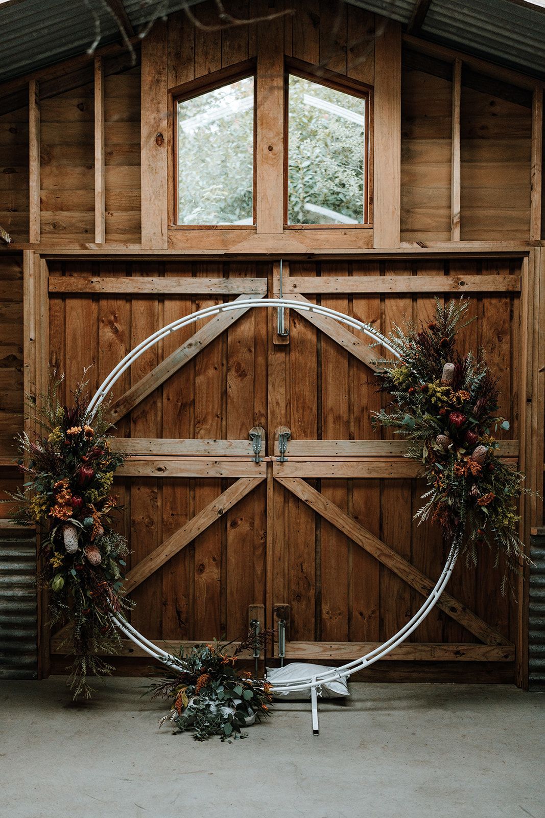 Rustic barn doors with a large white floral hoop wreath and greenery décor above and around them
