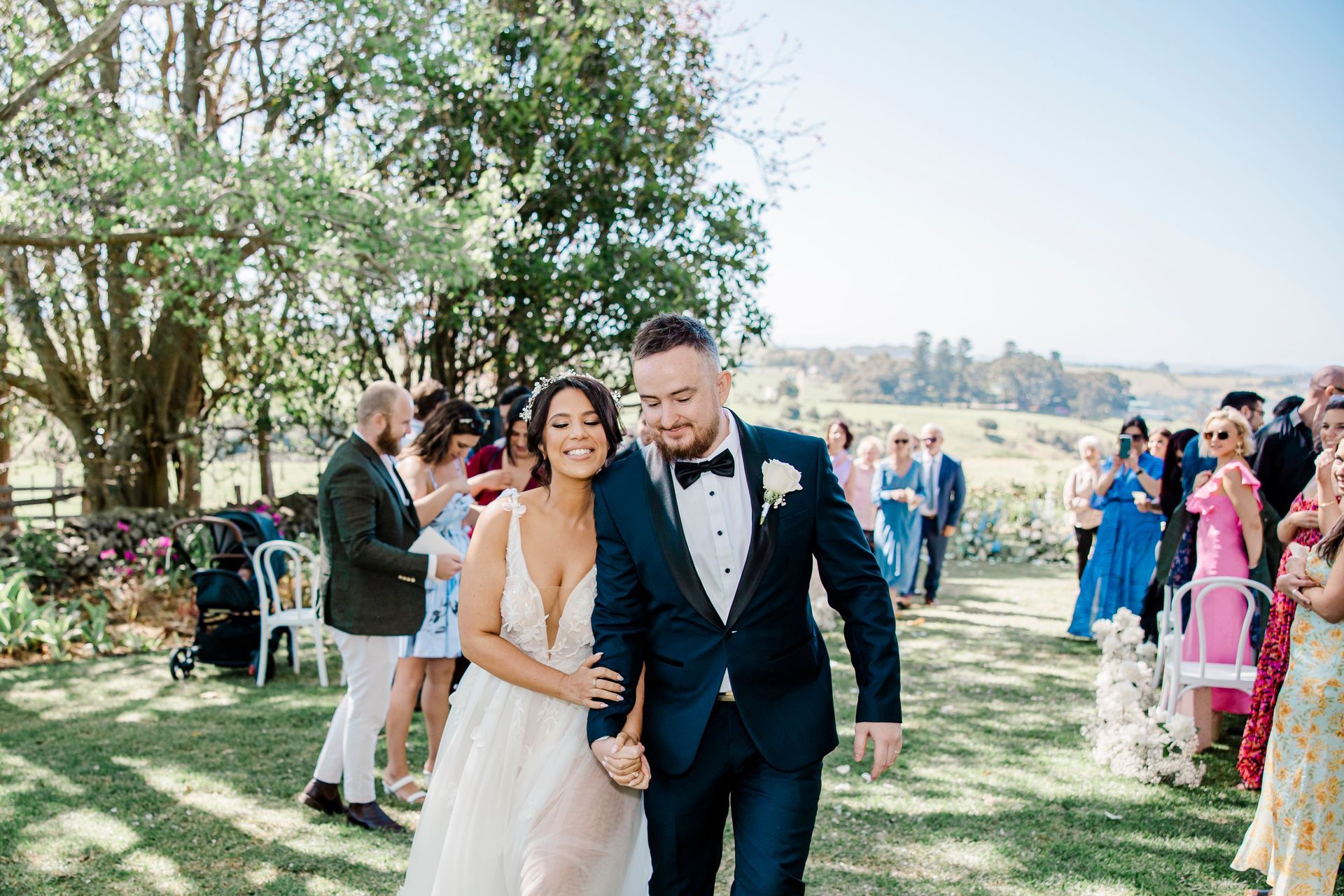 Newlyweds walking together outdoors at a sunny garden wedding ceremony