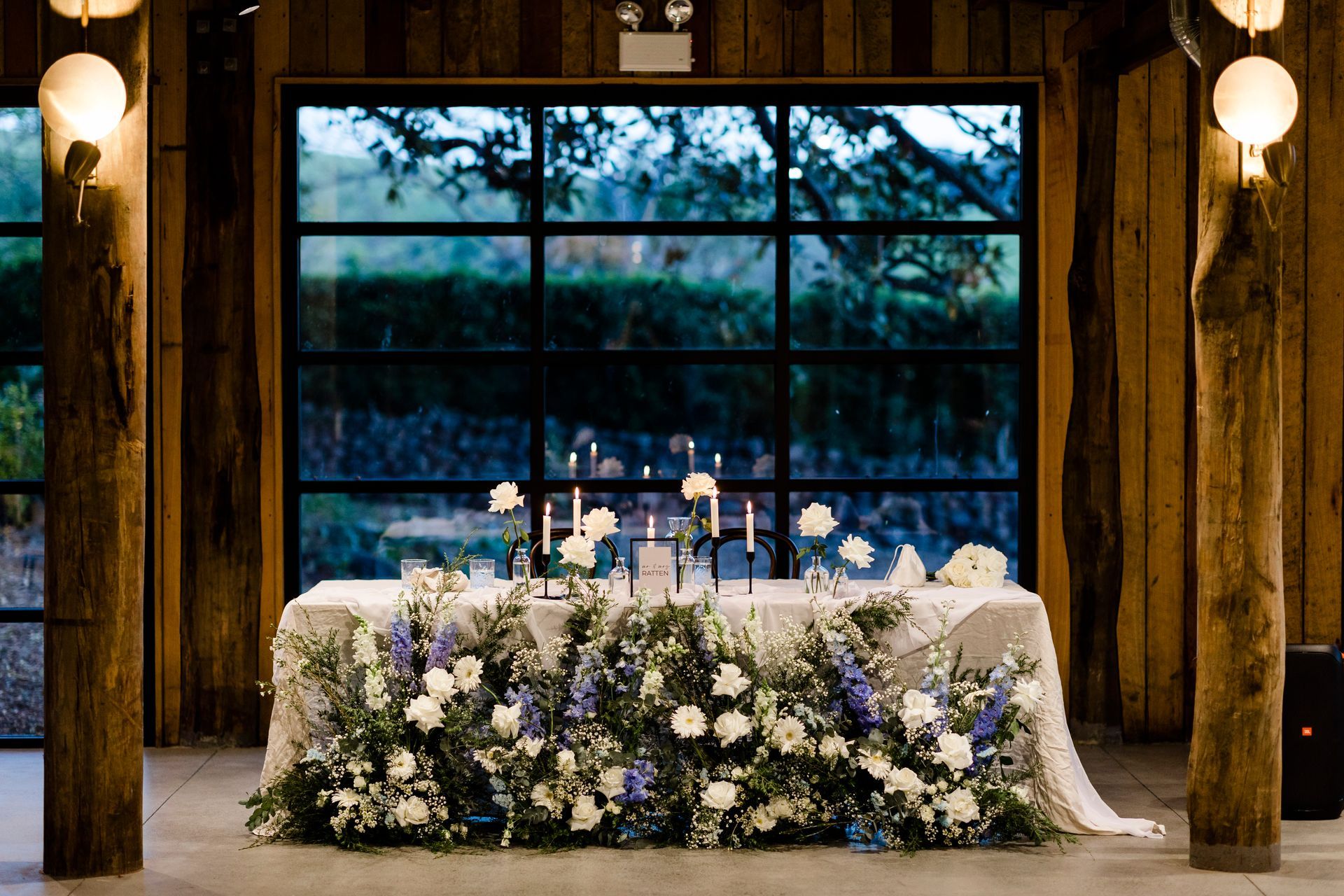 Wedding reception table with white floral arrangement in a rustic wooden venue