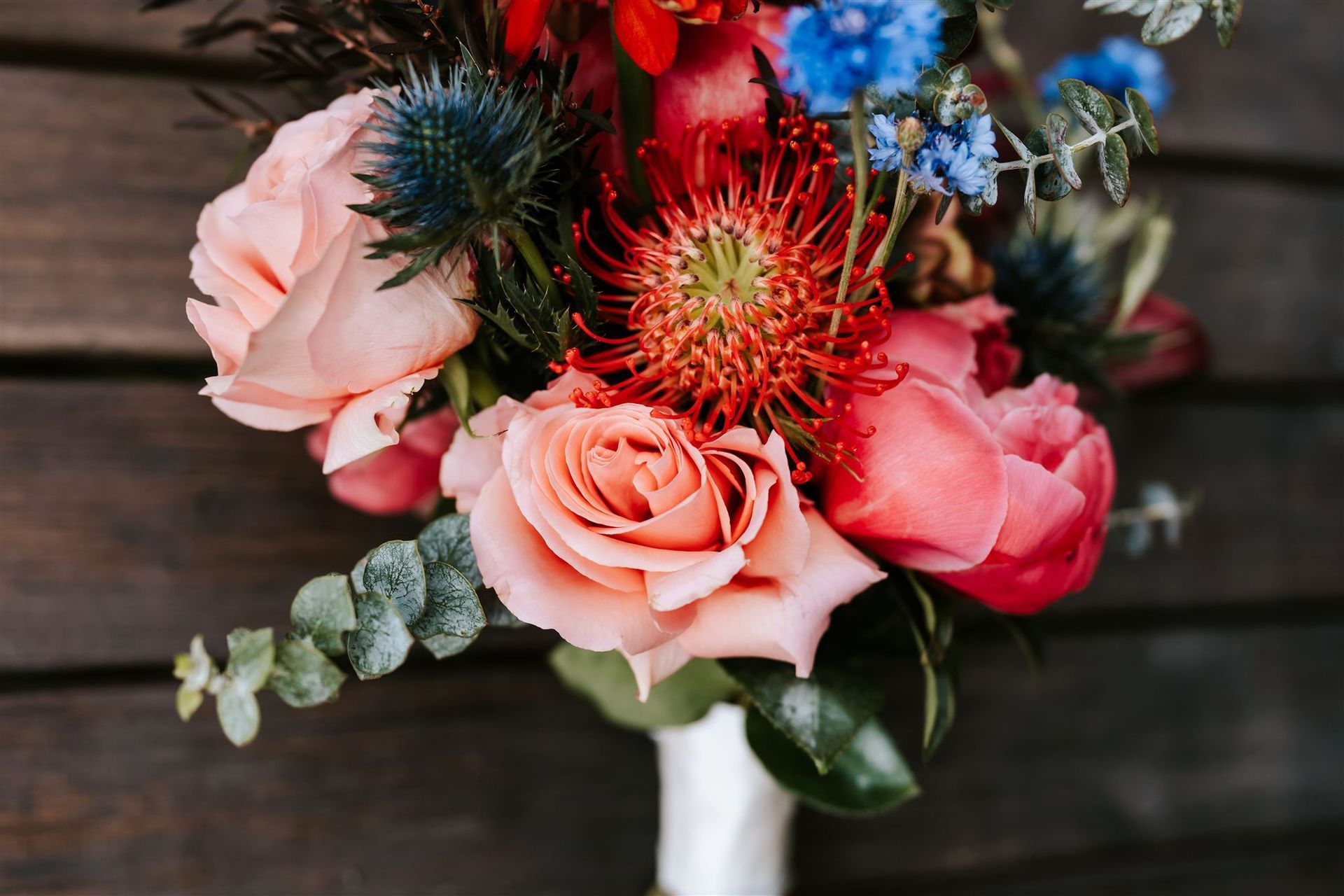 Pink roses and red flowers arranged in a bouquet on a wooden surface