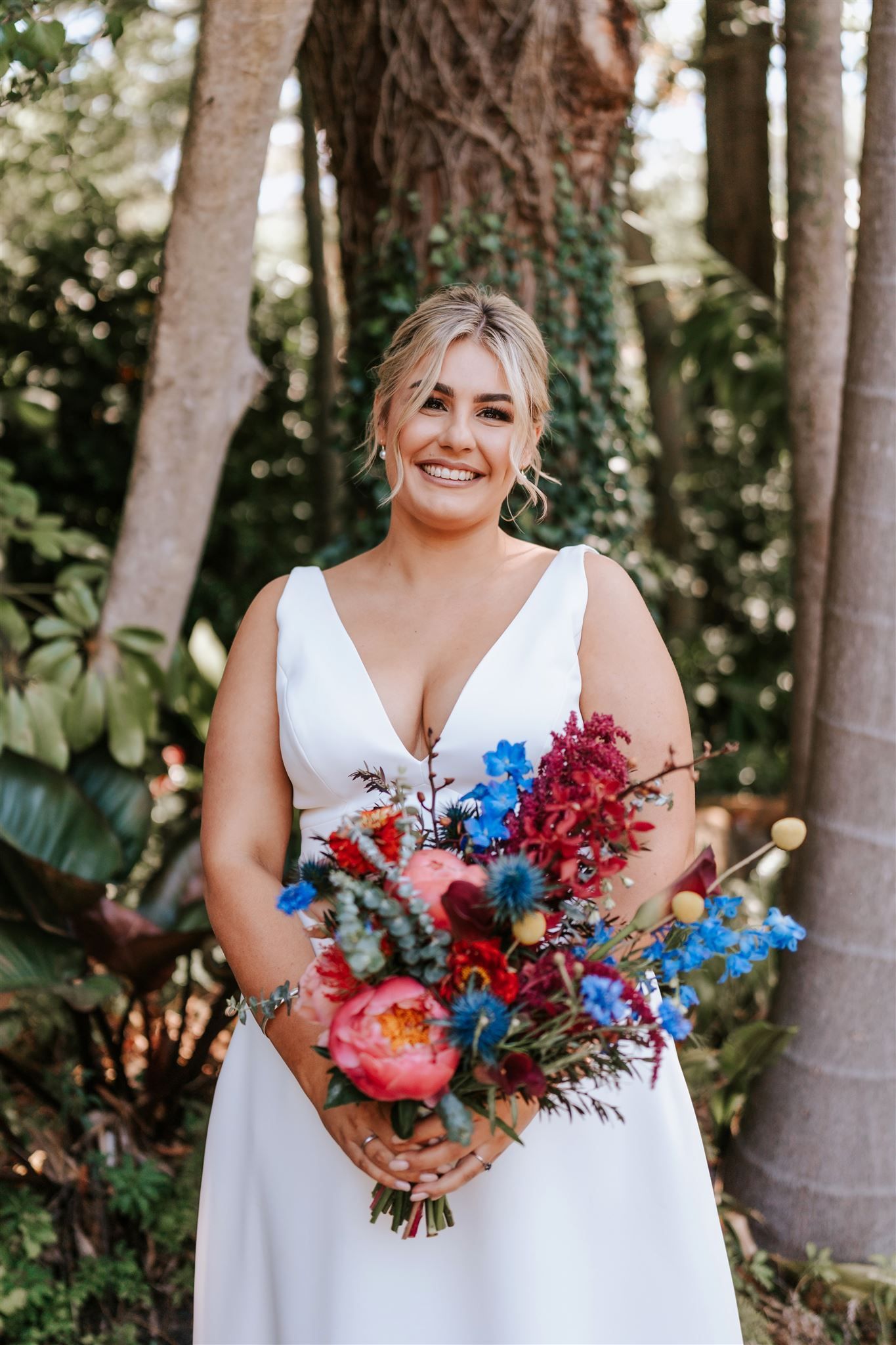 Woman in a white dress holding a colorful bouquet in a garden setting