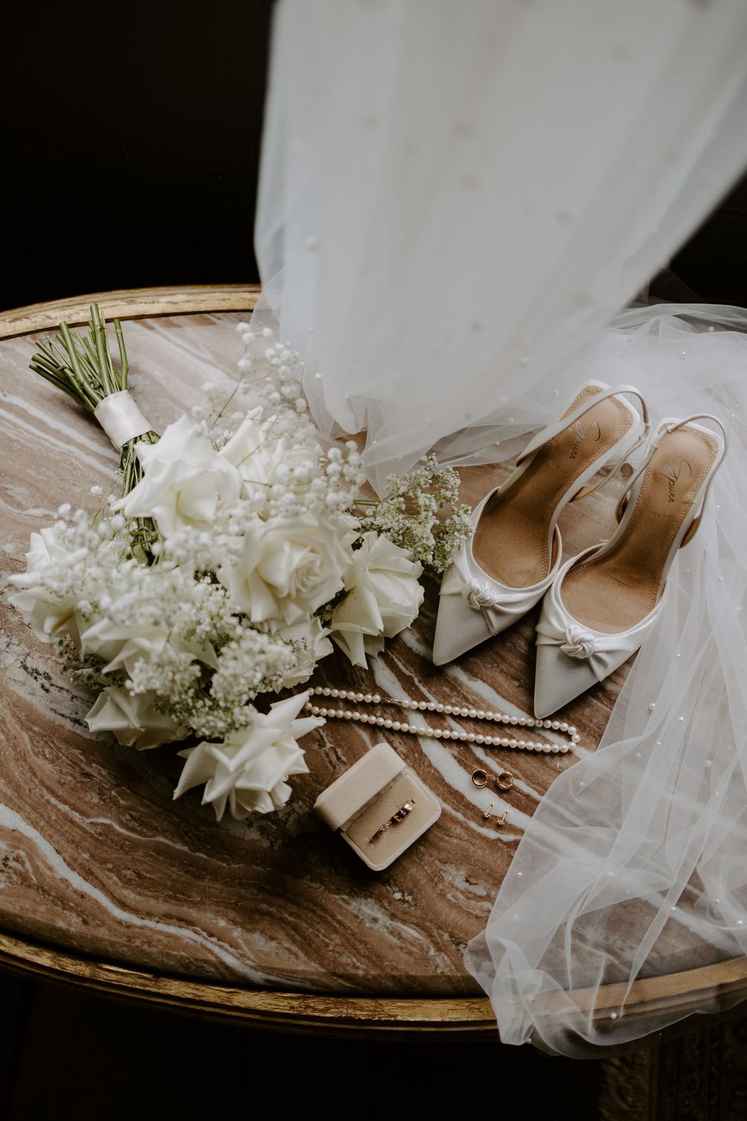 Wedding bouquet and shoes on a rustic tray with white veil fabric
