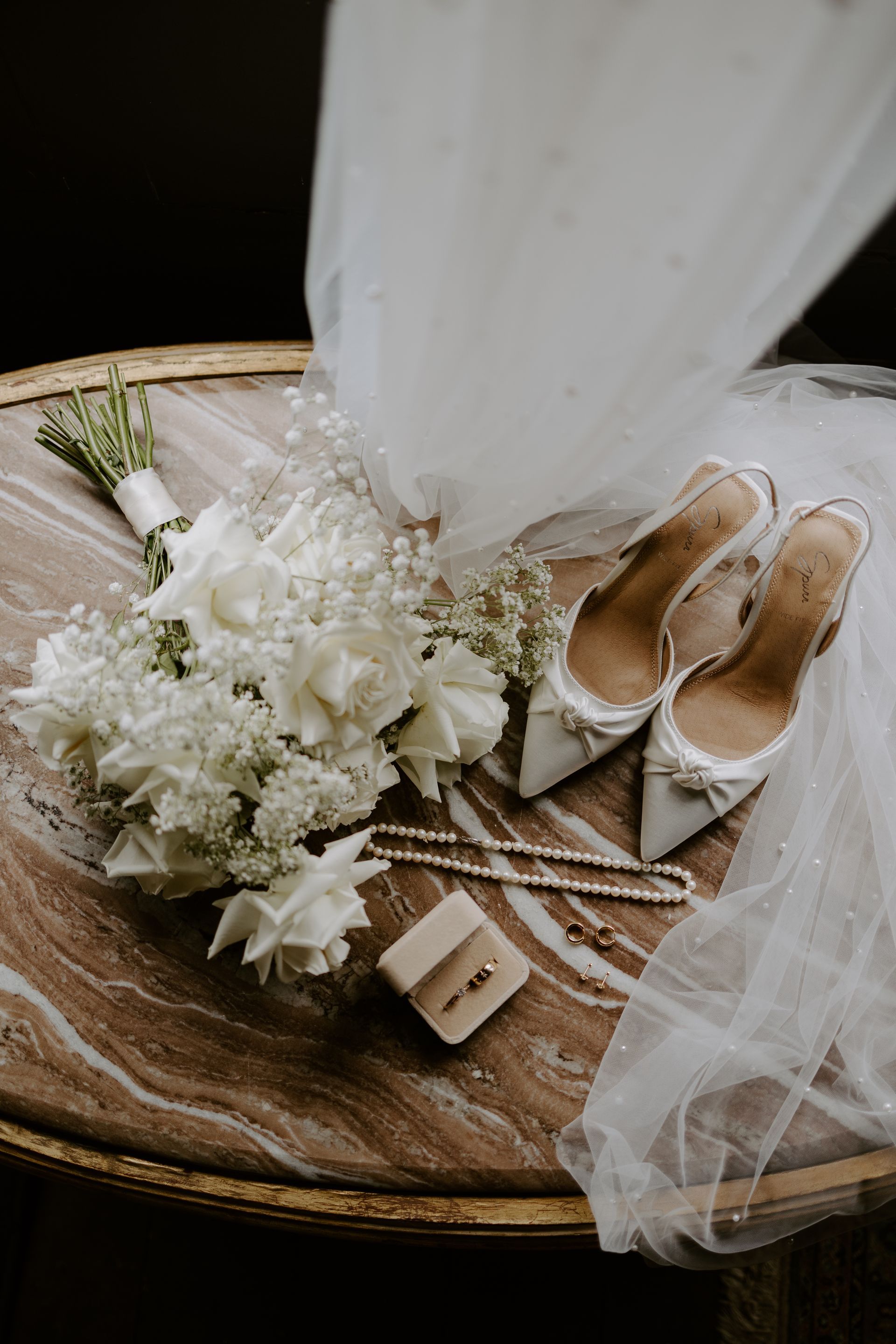 White floral bouquet with beige shoes and tulle on a decorative tray