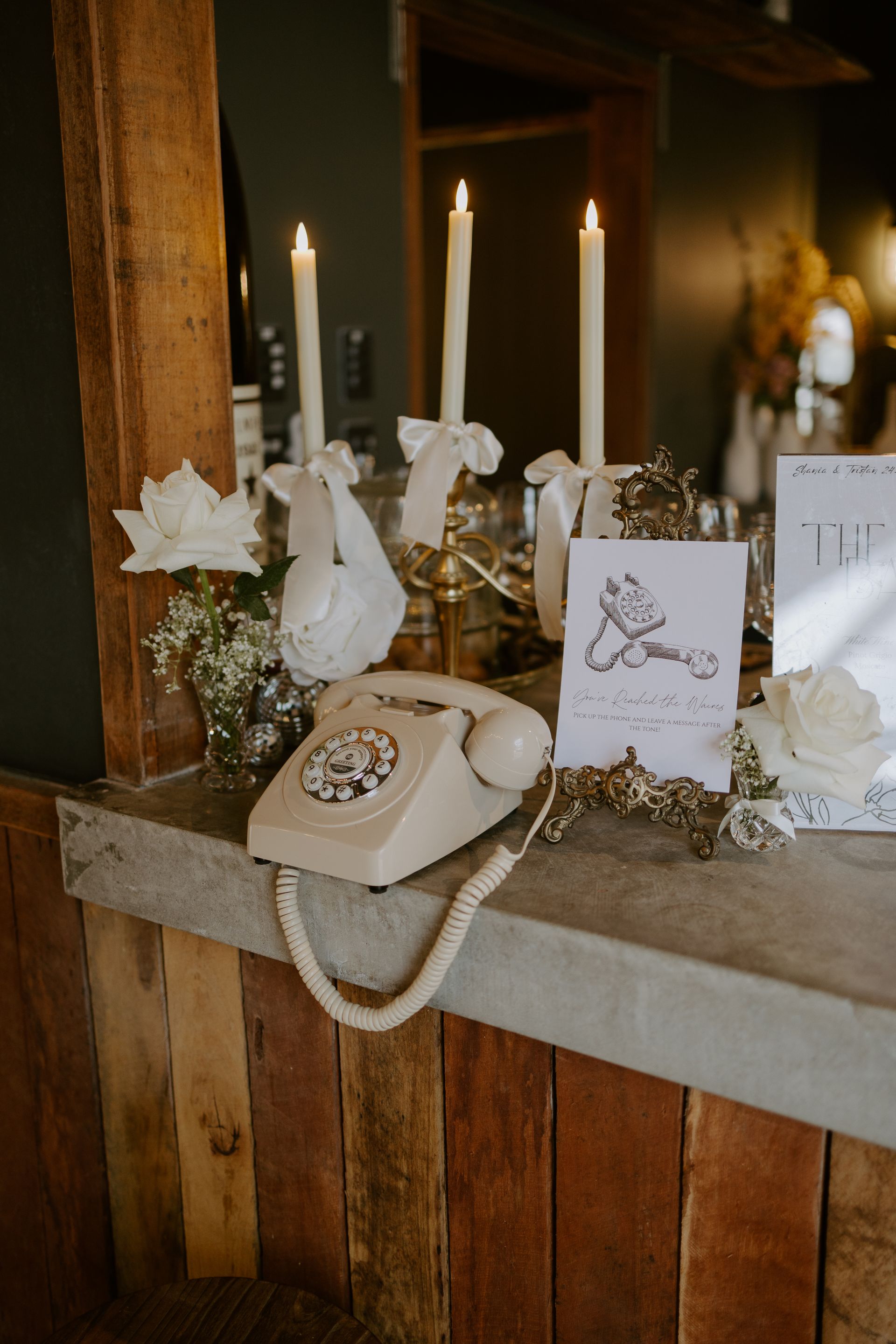 Rustic table display with candles, white flowers, cards, and a vintage rotary phone