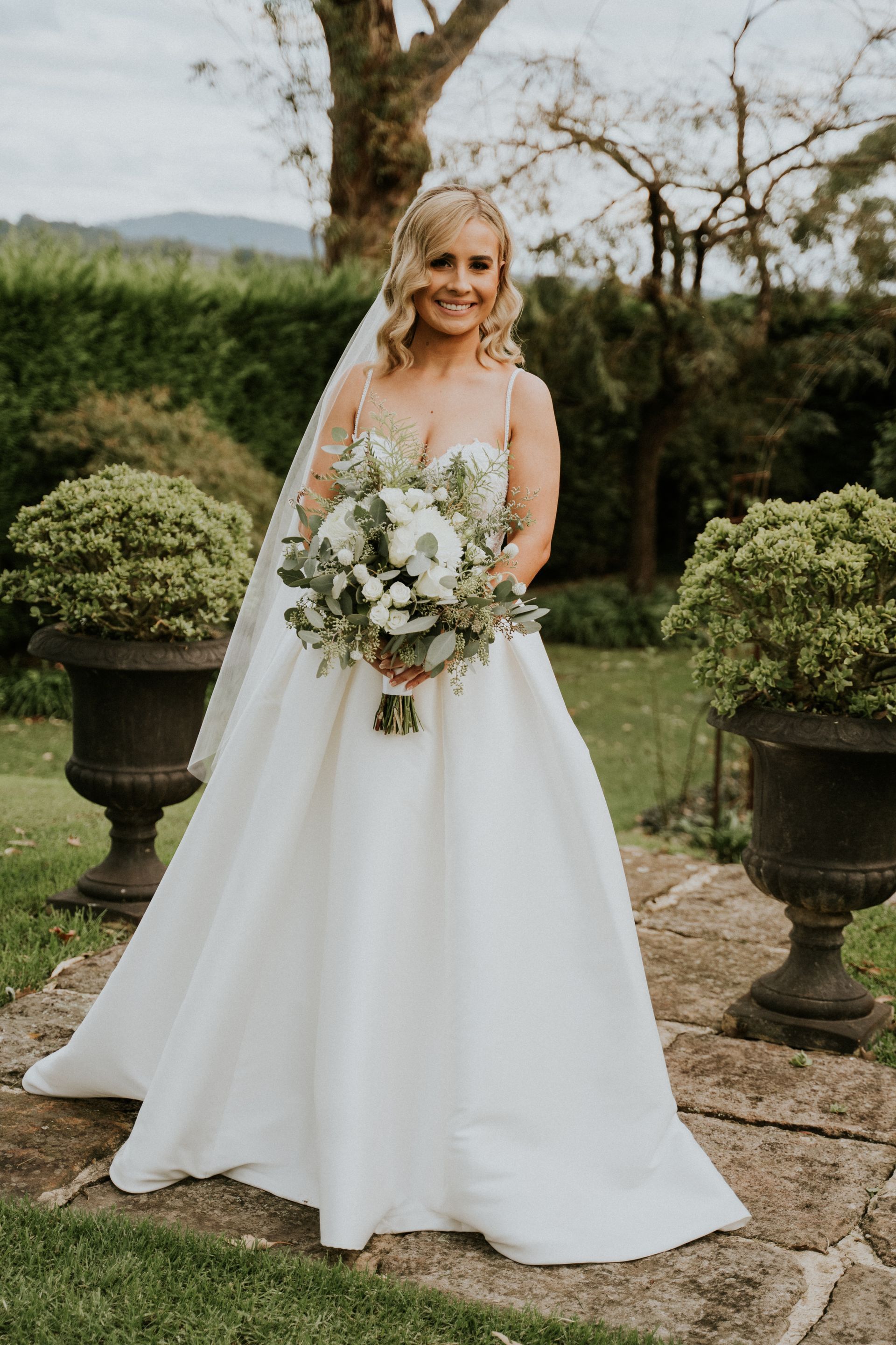 Bride in a white gown holding a bouquet in a garden setting