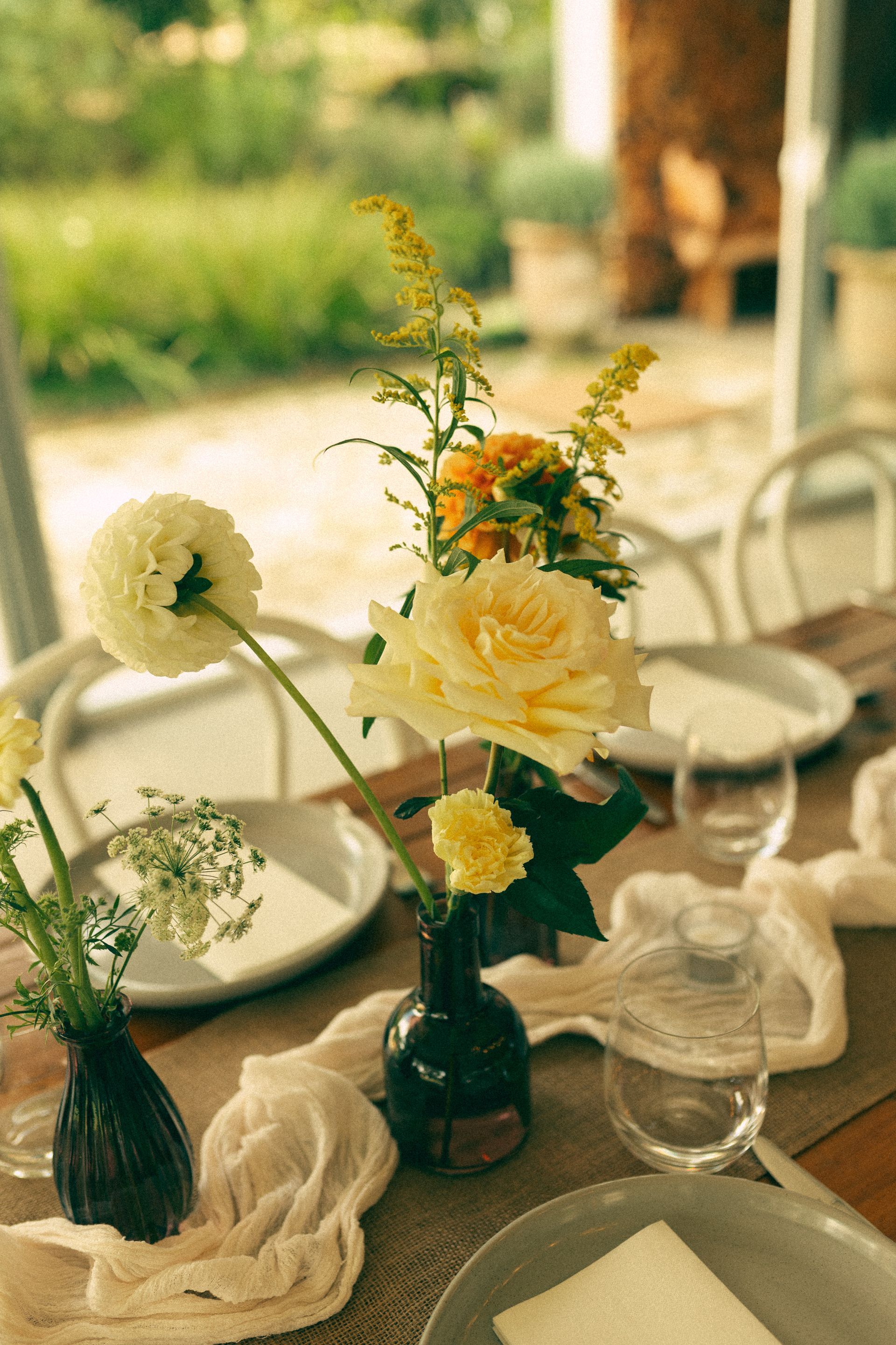 Flower arrangement in small green vases on a dining table by a sunny window