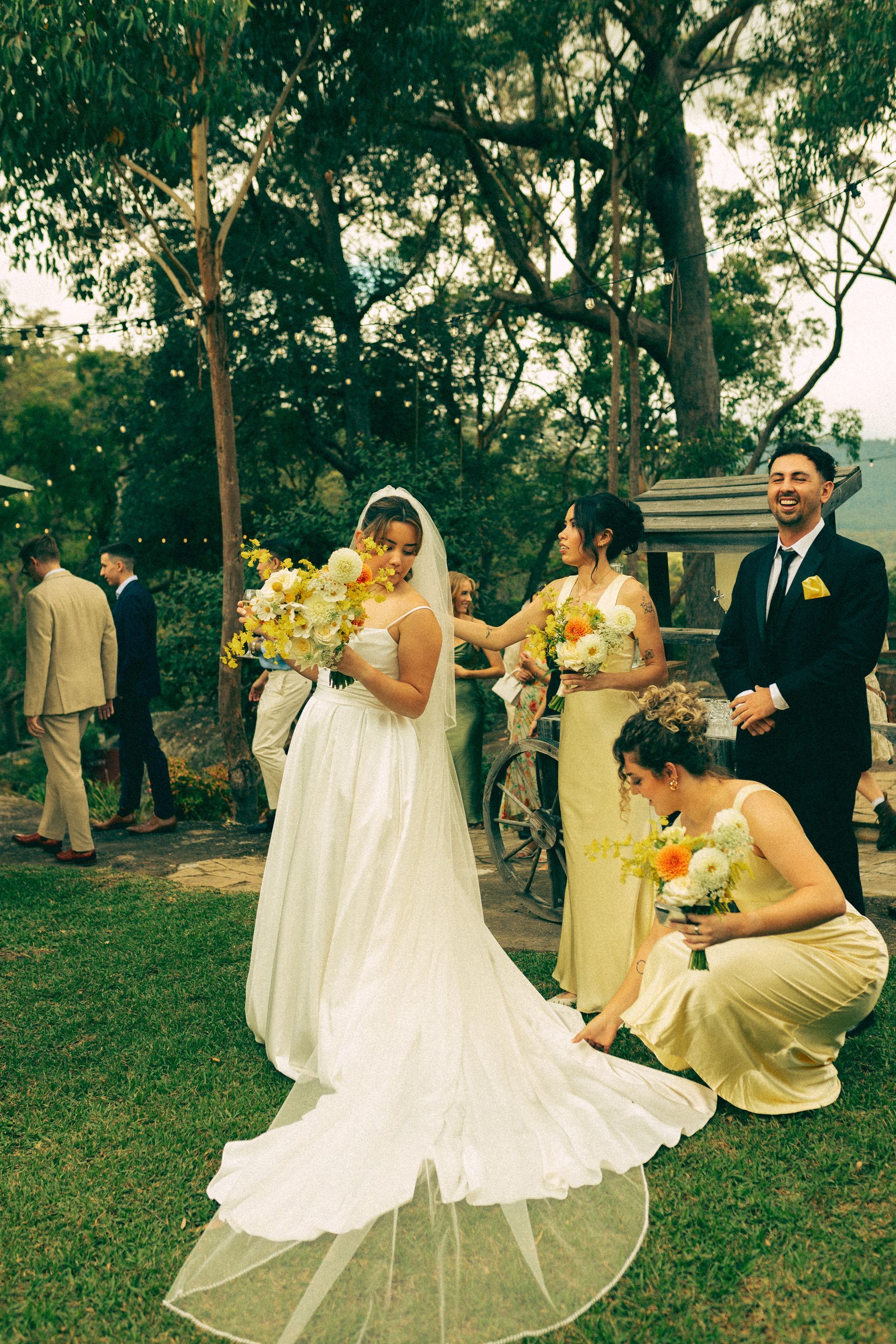 Bride and wedding party posing outdoors in a garden, with bouquets and formal attire