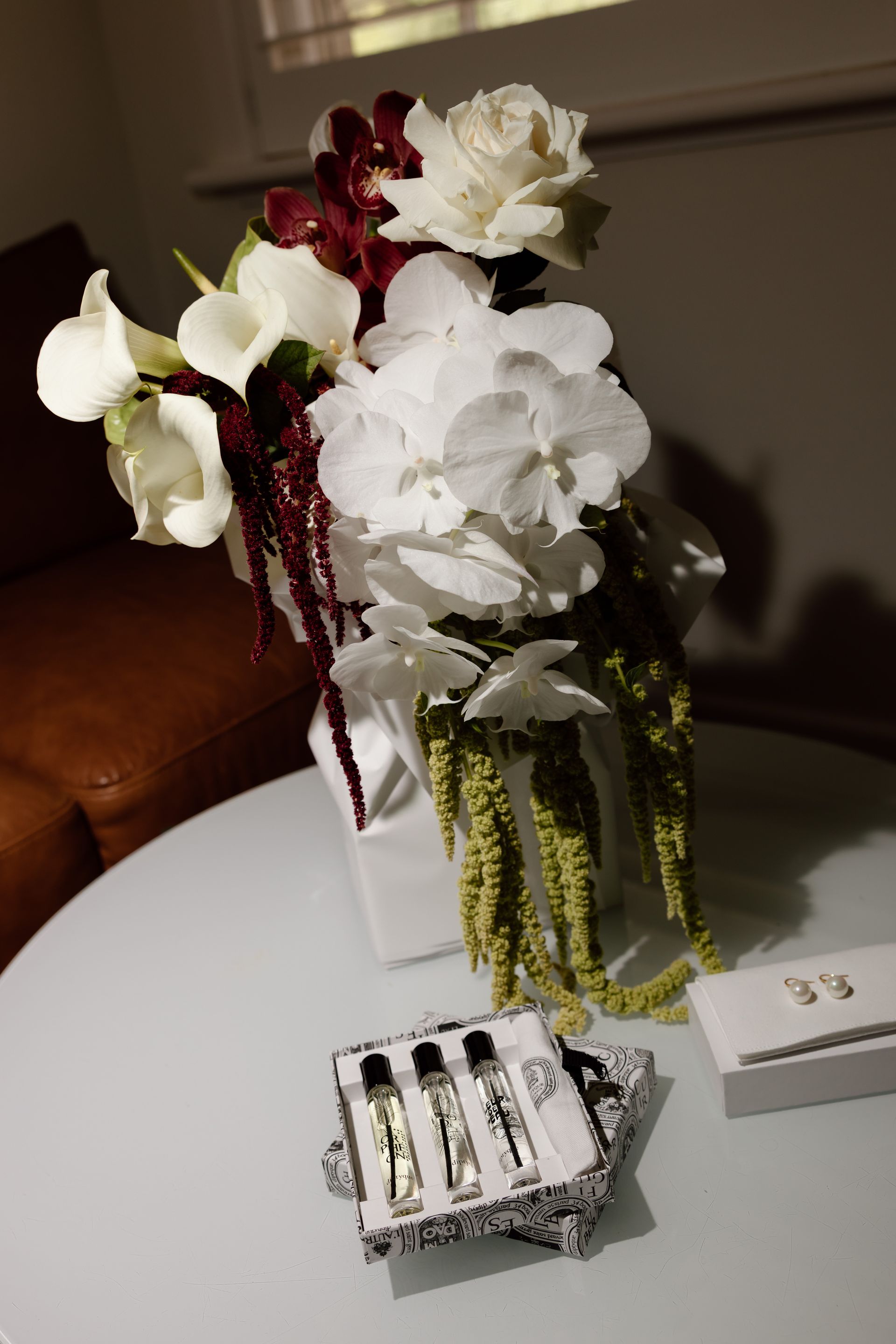 White and burgundy floral arrangement on a table beside small boxed items and a booklet