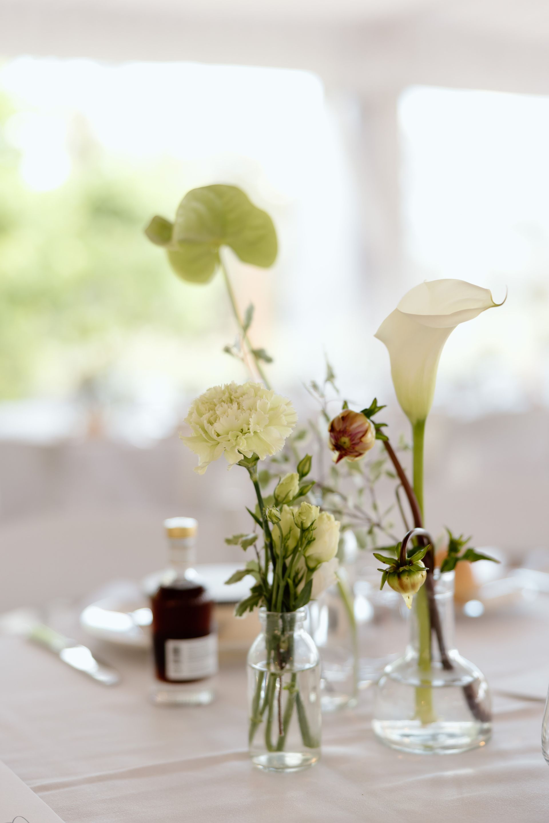 Elegant table centerpiece with white and green flowers in glass vases on a softly lit dining table
