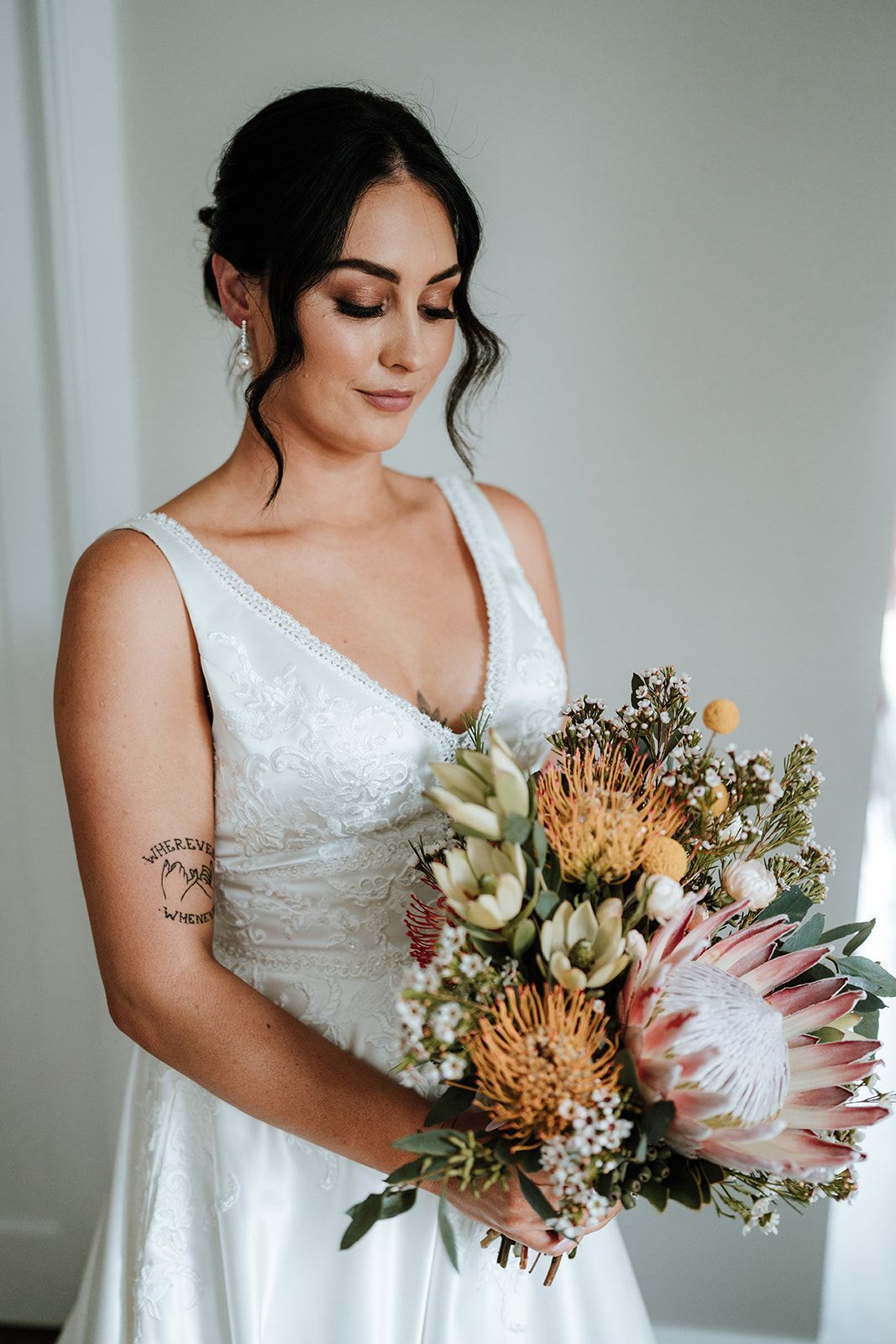 Woman in a white dress holding a bouquet of pastel flowers indoors