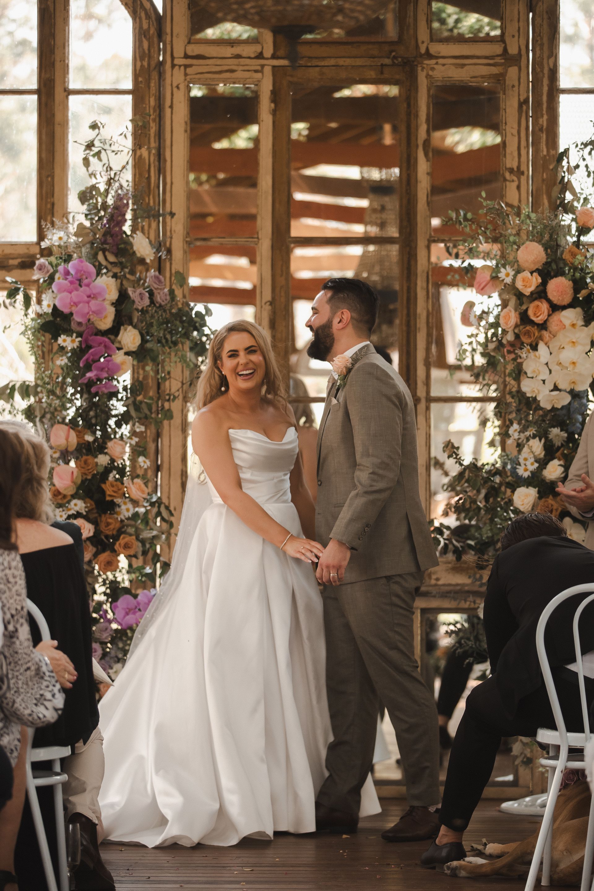 Bride and groom holding hands in a flower-filled wedding ceremony venue