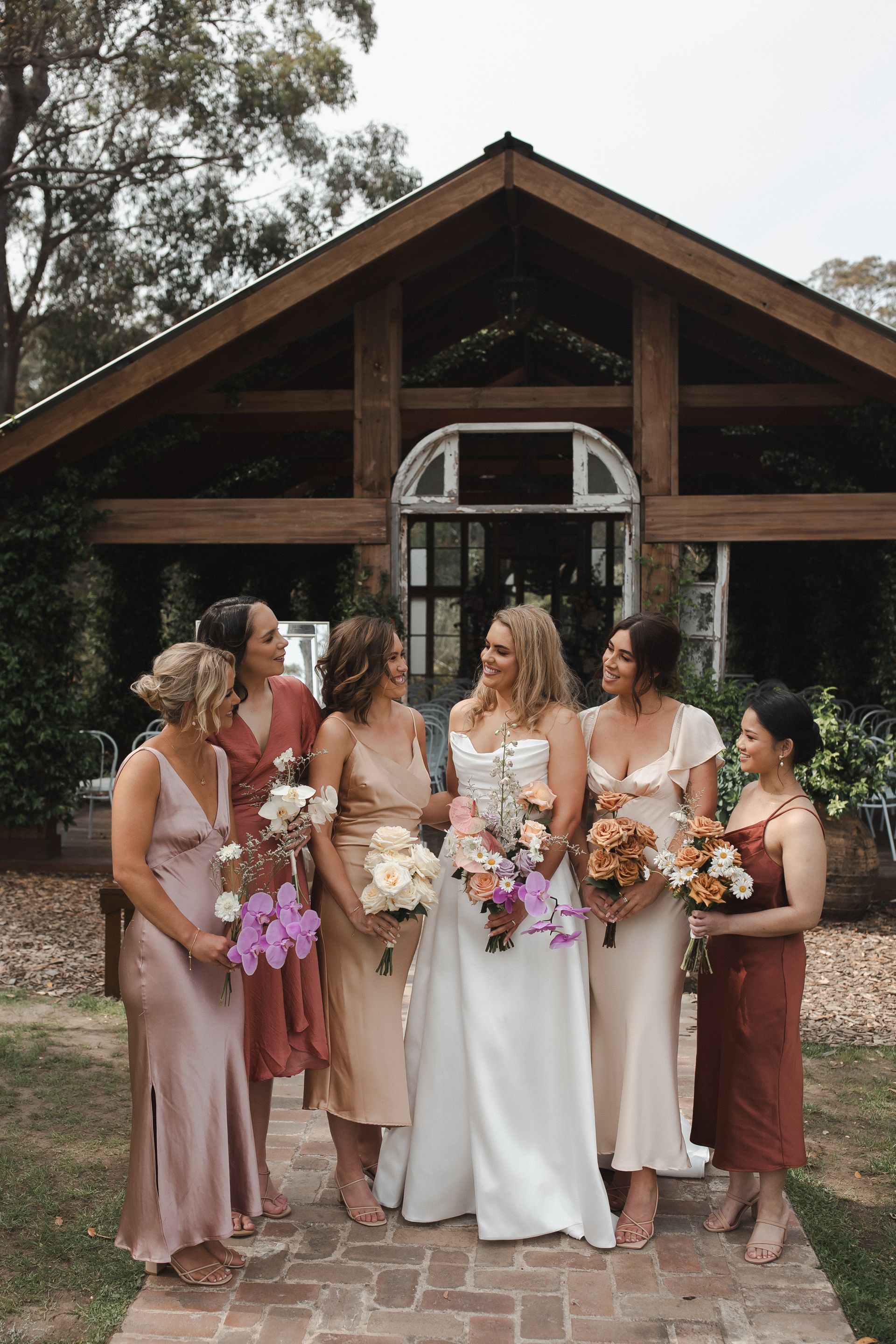 Bridesmaids and bride posing with bouquets in front of a rustic chapel entrance