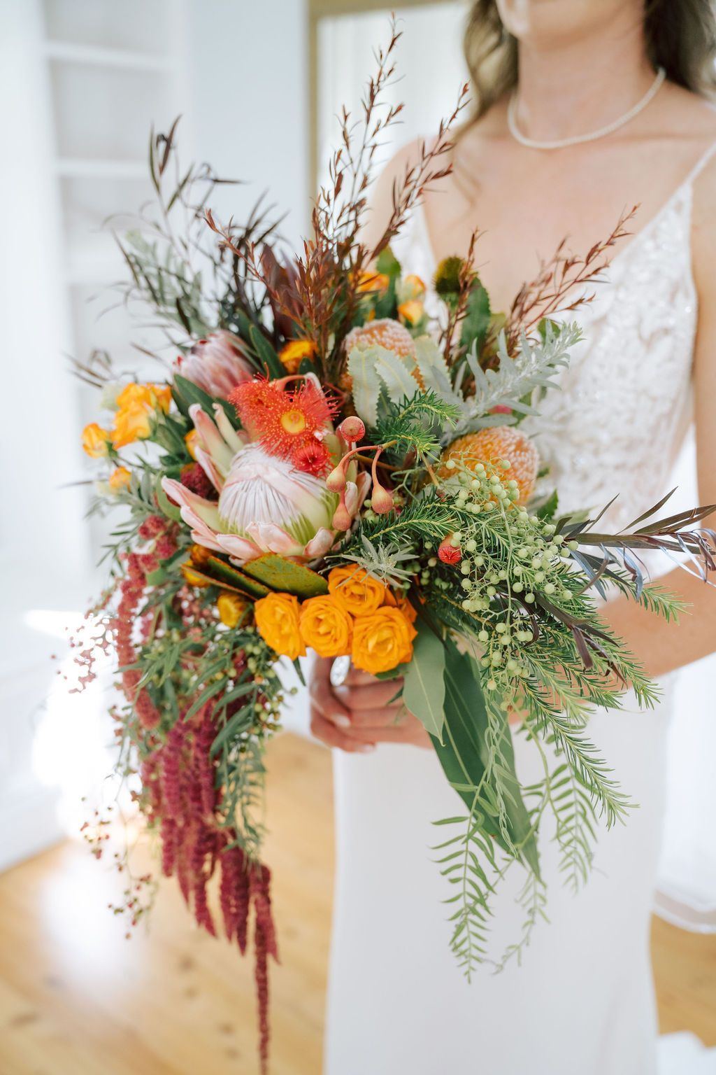 Bride holding a colorful wildflower bouquet with orange and red blooms and greenery