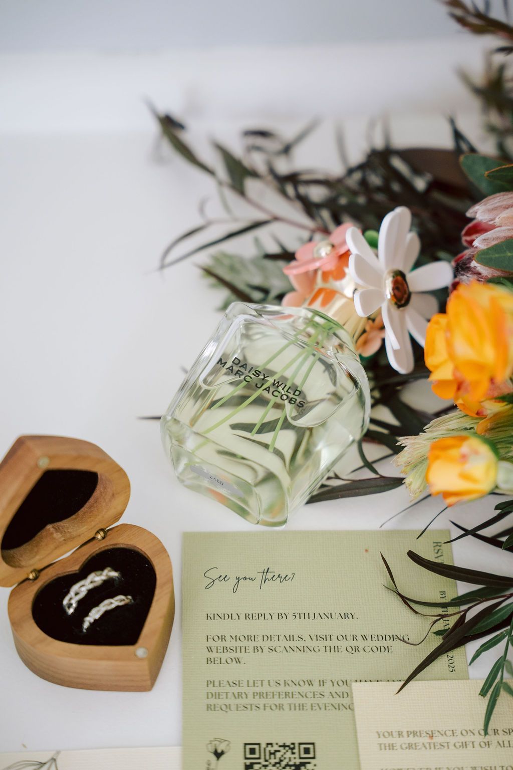 Perfume bottle with flowers, a heart-shaped jewelry box, and a floral card on a light surface