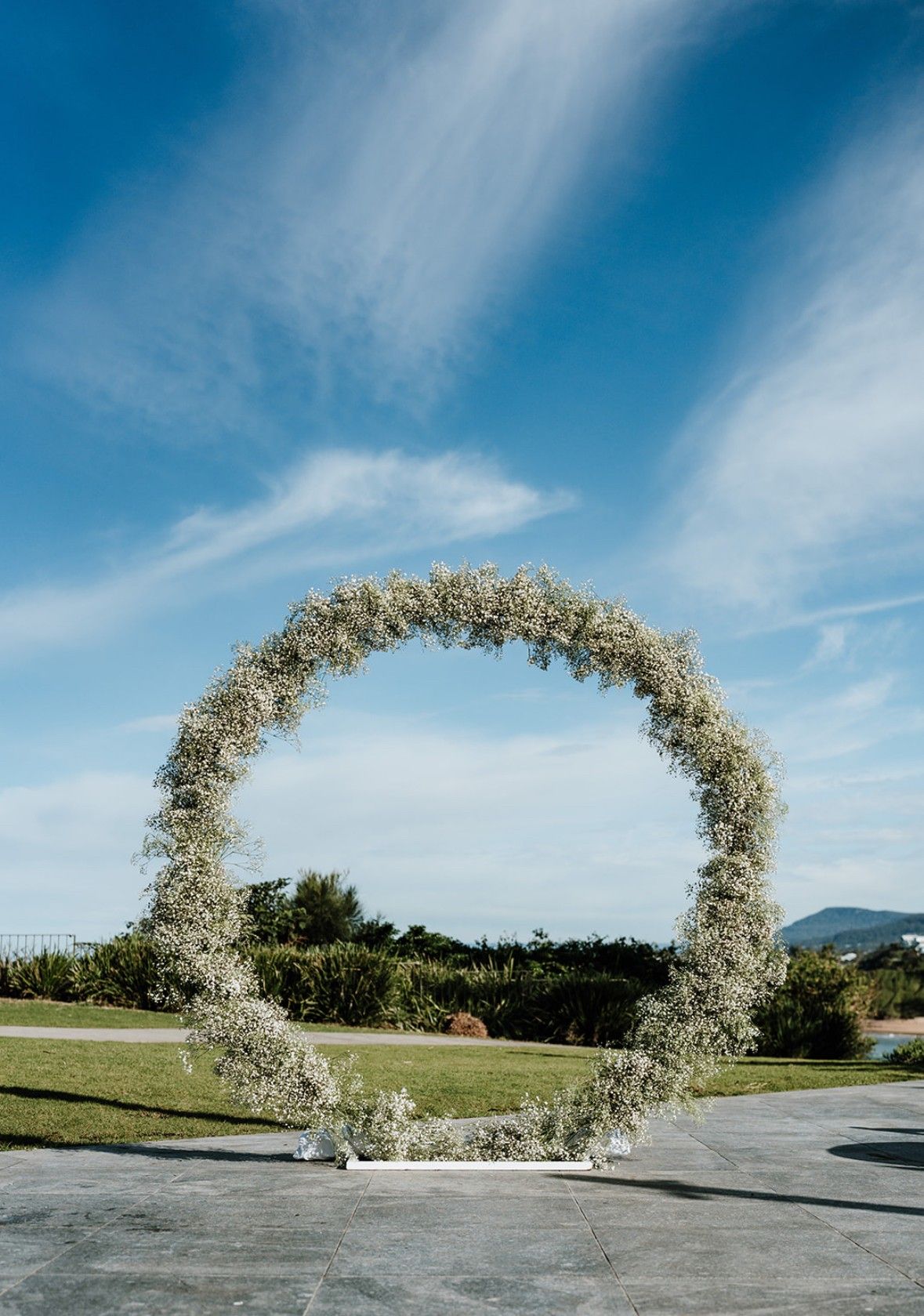 Flower-covered circular sculpture outdoors under a blue sky