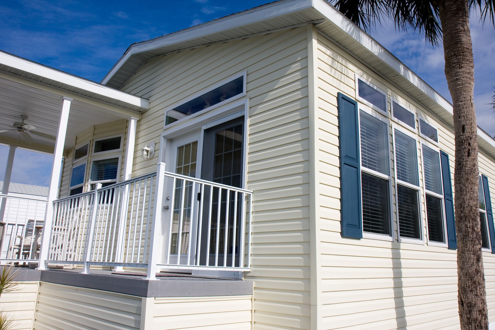 A white mobile home with blue shutters and a porch