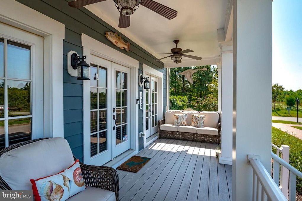 A porch with a couch , chair , and ceiling fan.