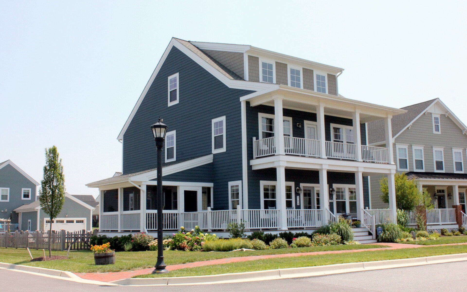A large blue house with a white porch in a residential neighborhood.