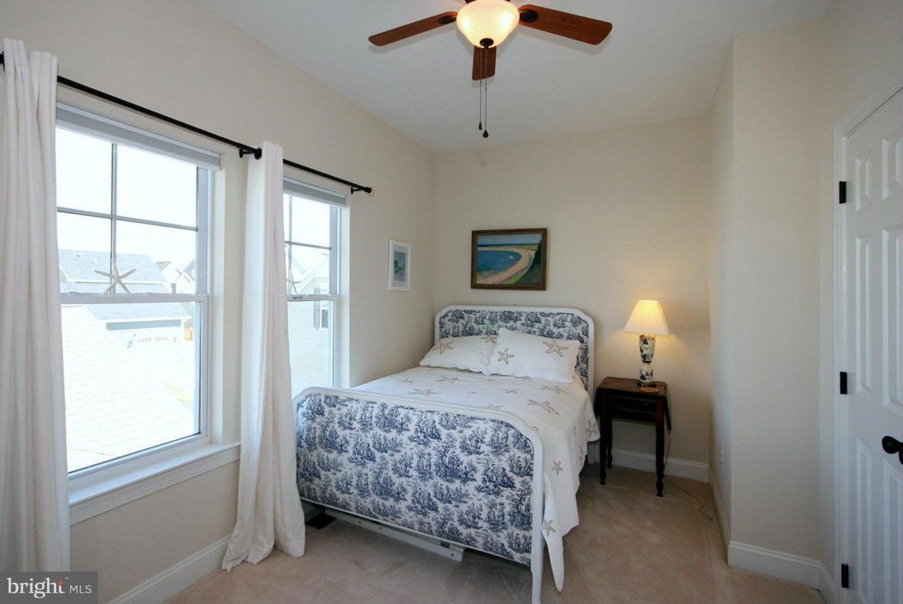 A bedroom with a bed and a ceiling fan.