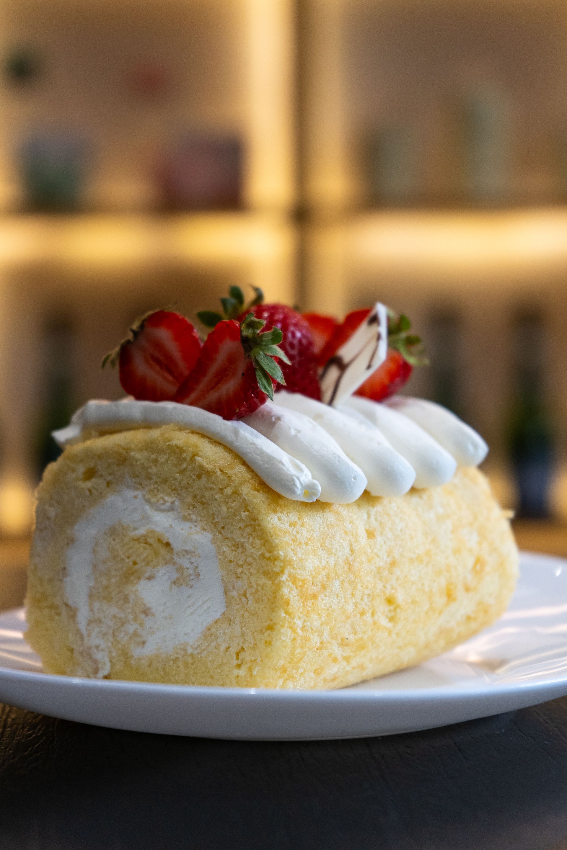 Pastel suizo cubierto con crema batida y fresas en un plato blanco.