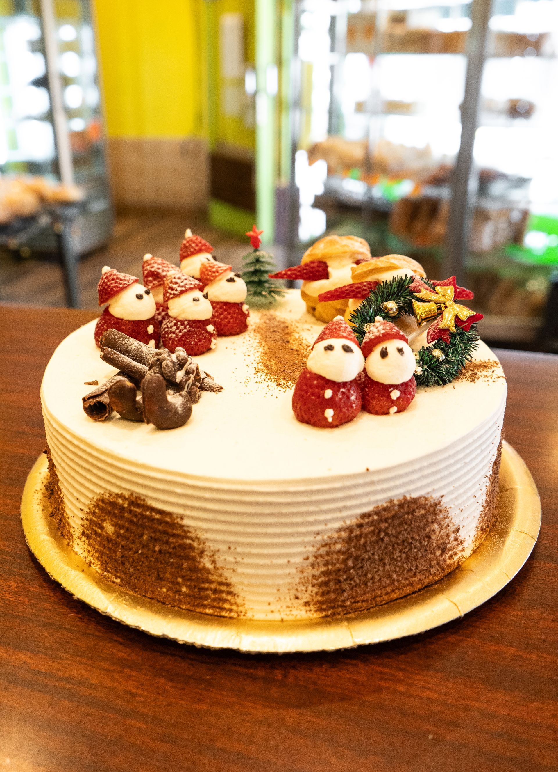 Pastel de Navidad con adornos de Papá Noel sobre una mesa de madera en una panadería.