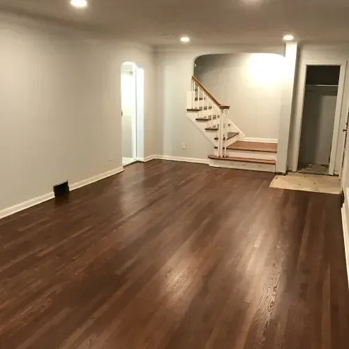 An empty living room with hardwood floors and stairs.
