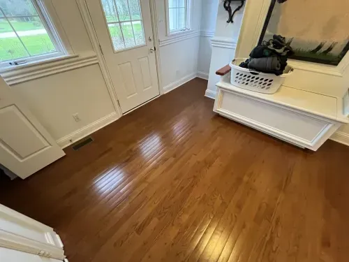 A hallway with hardwood floors and a white bench.
