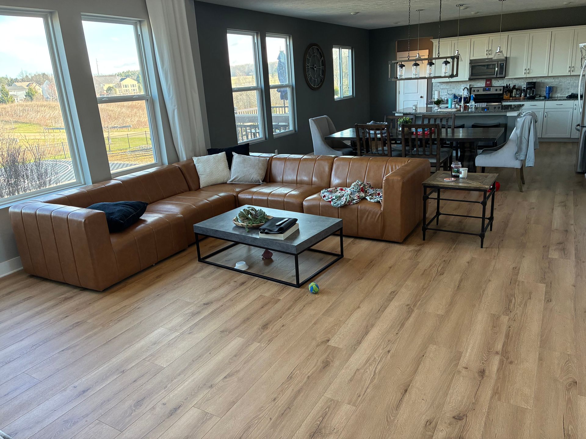 Modern living room with tan sectional, glass coffee table, and open kitchen view
