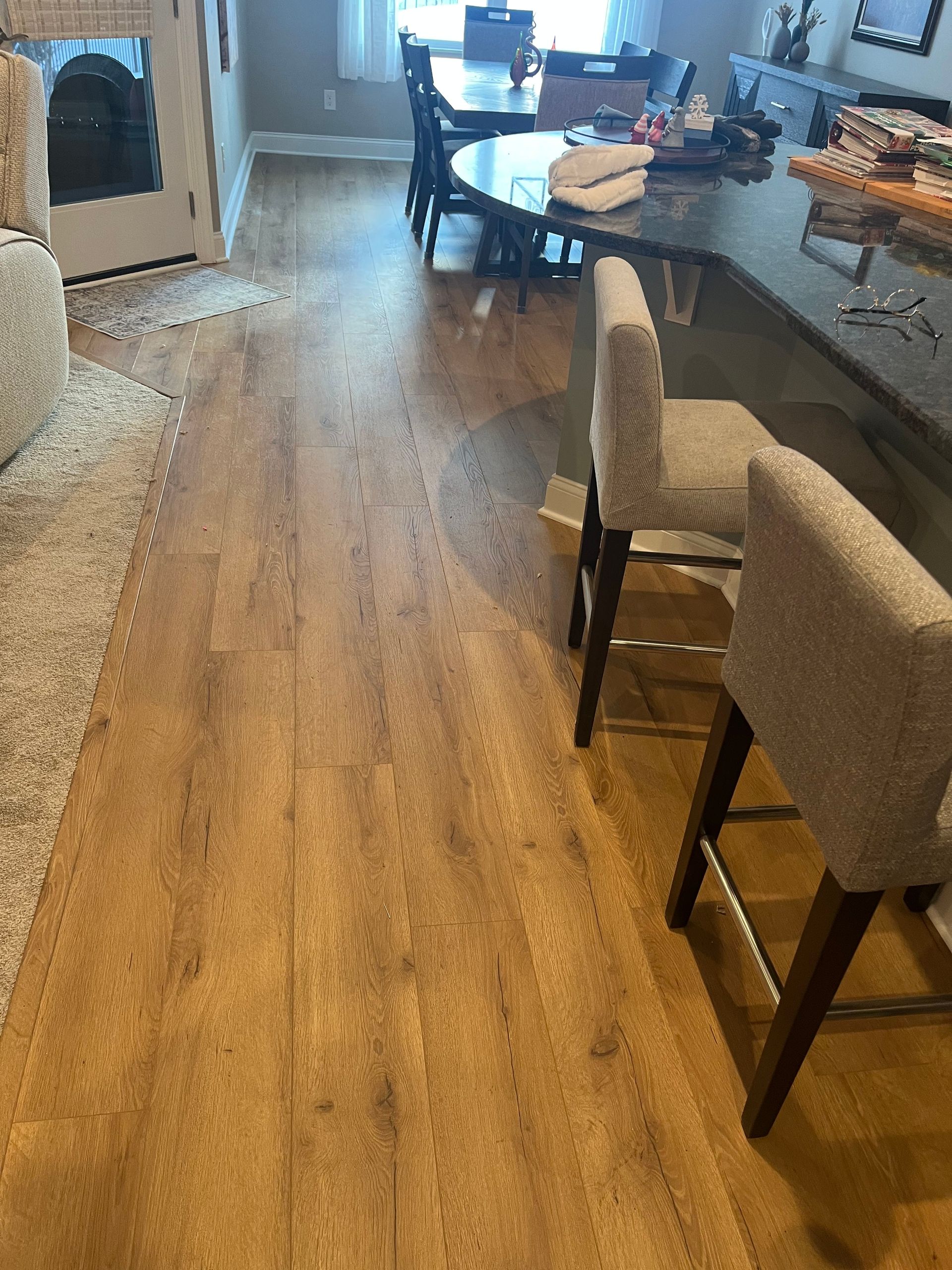 Modern kitchen and dining area with a long wood table, beige chairs, and hardwood floors.