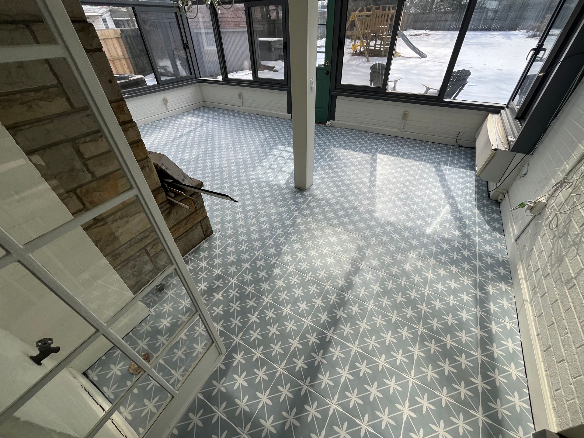 Bright tiled entryway with large windows, stone wall, and a central support column.