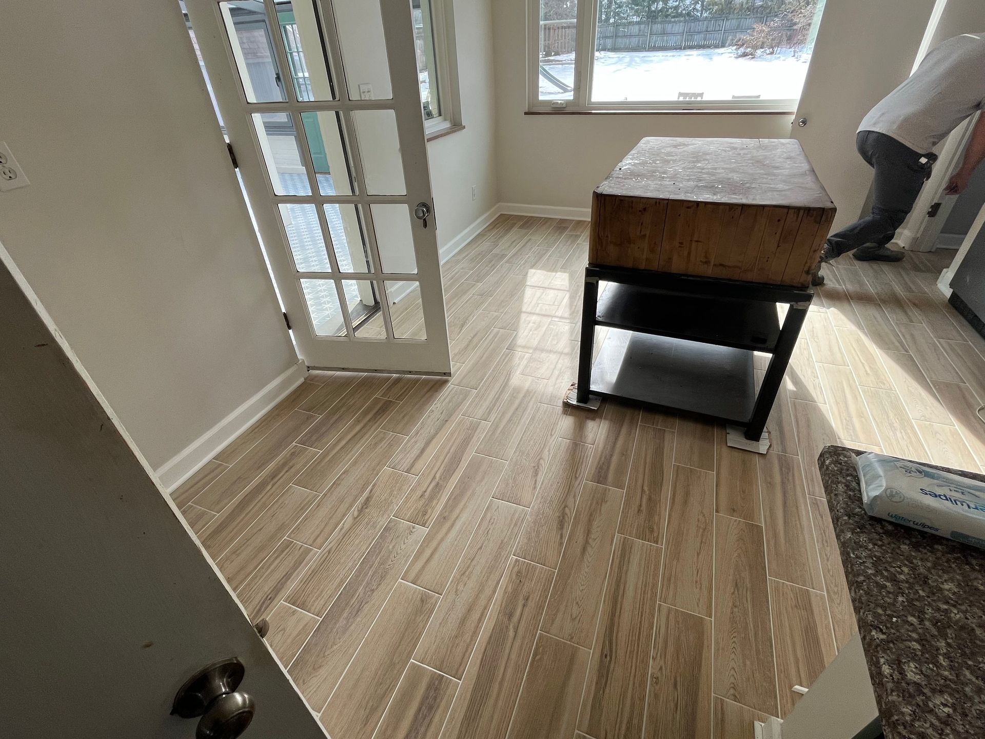 Empty room with light wood floors, French doors, a window, and a small table near the wall.