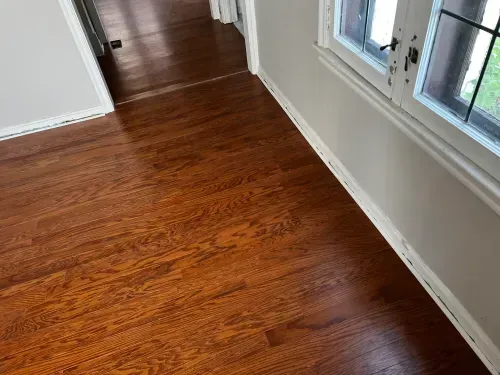 A hallway with hardwood floors and two windows.