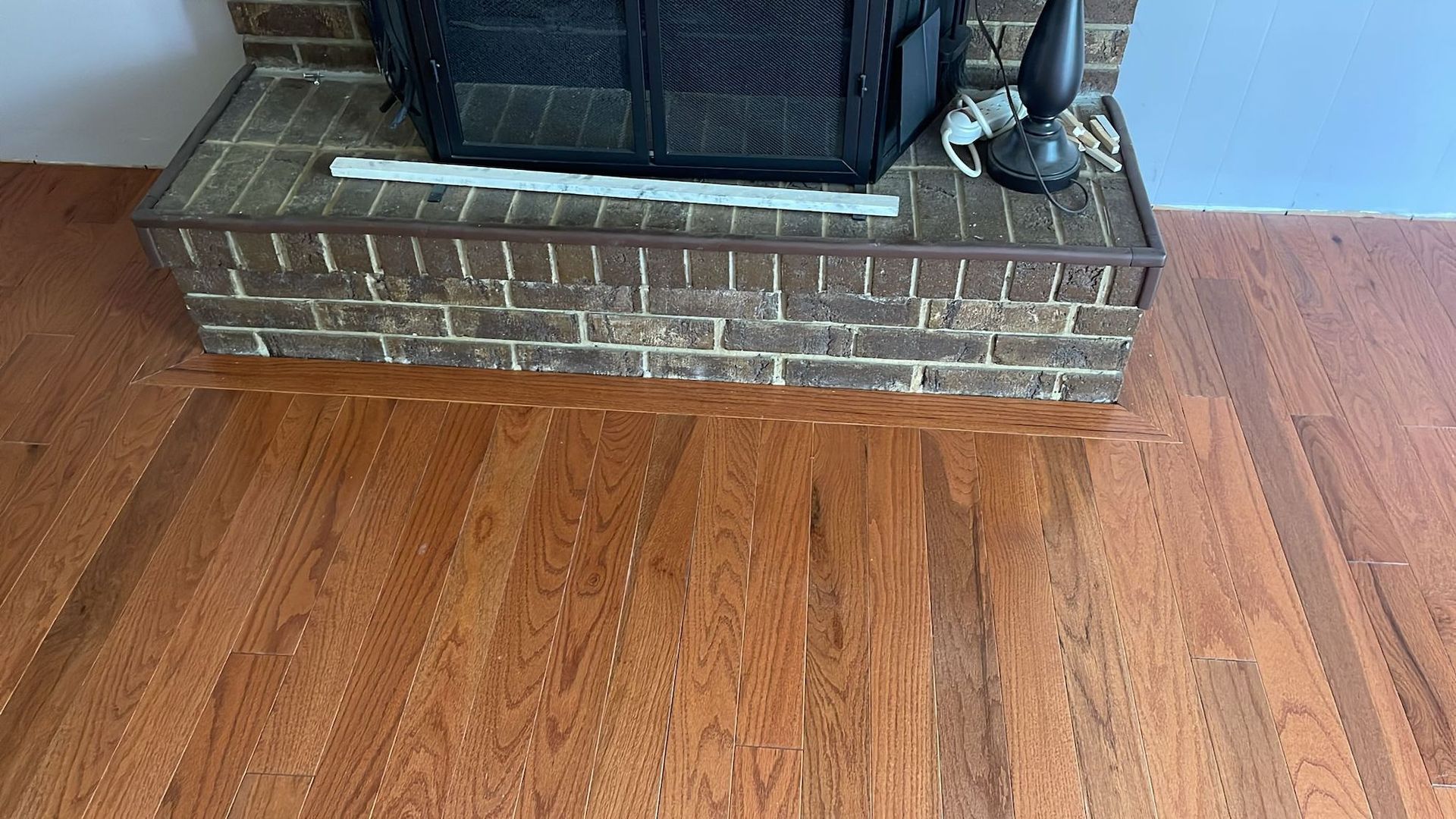 Brick fireplace hearth and dark wood flooring.