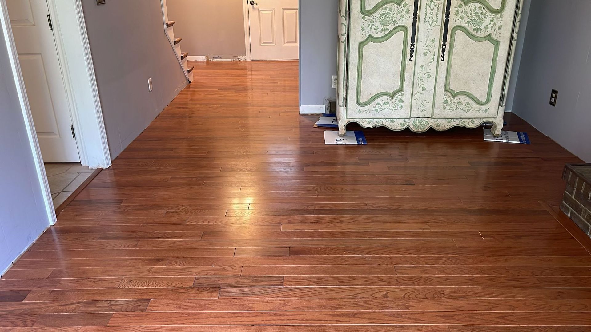 Hardwood floor with white cabinet and open doorway.