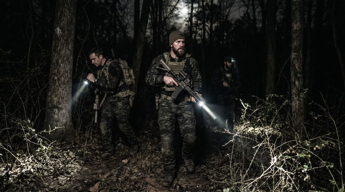 Hunters searching through forest at night for hogs