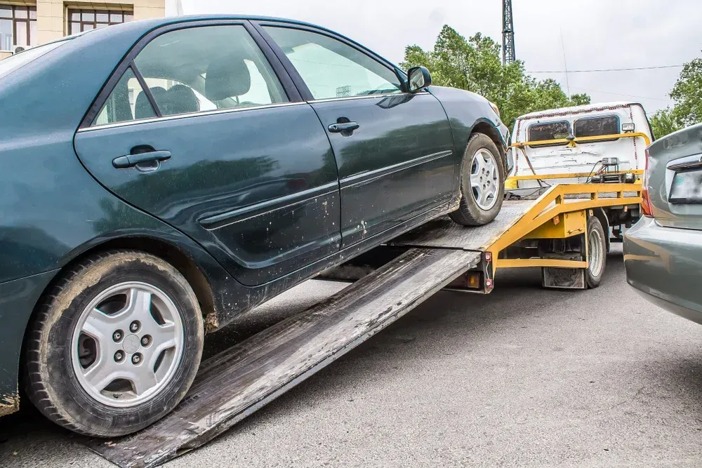 Green car being towed onto a flatbed tow truck in a parking lot. — Mission Truck Training in Mountain Creek, QLD