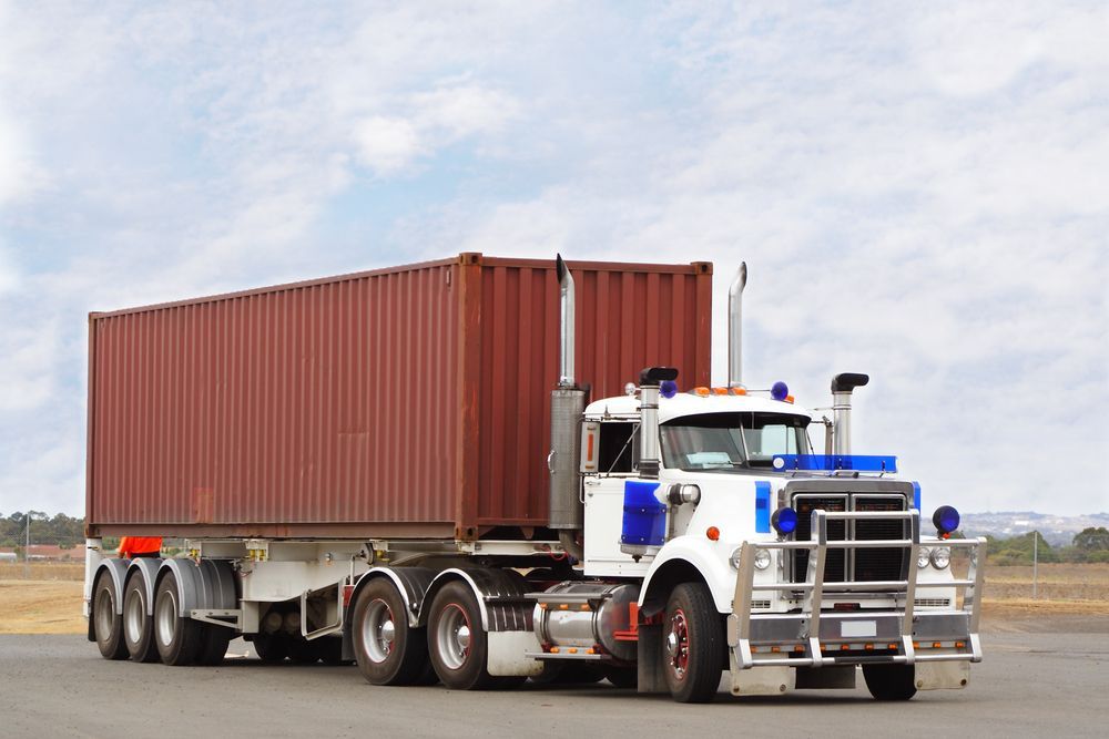 Semi-truck With a Red Container Driving on a Road Under a Cloudy Sky — Mission Truck Training in Mountain Creek, QLD