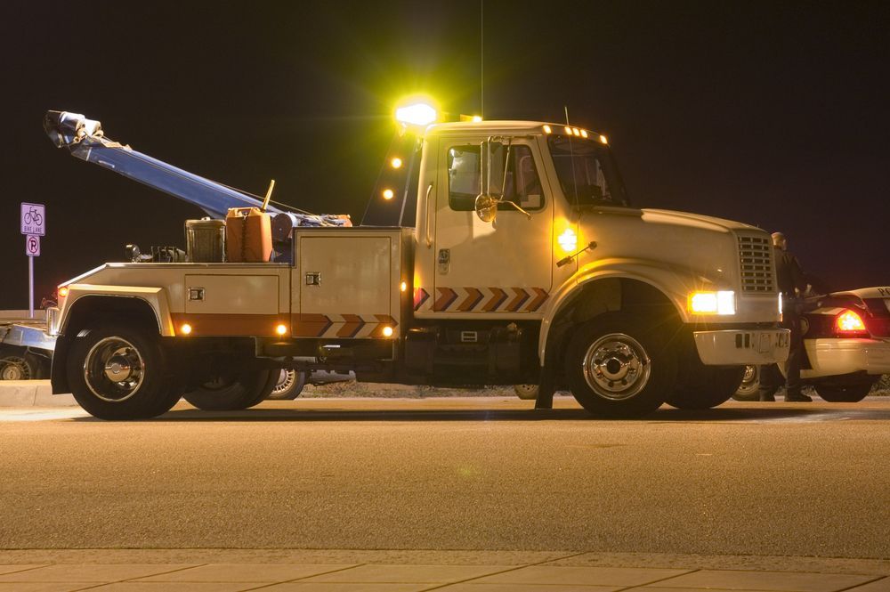 Tow Truck Illuminated at Night, Towing a Car in a Parking Lot — Mission Truck Training in Mountain Creek, QLD
