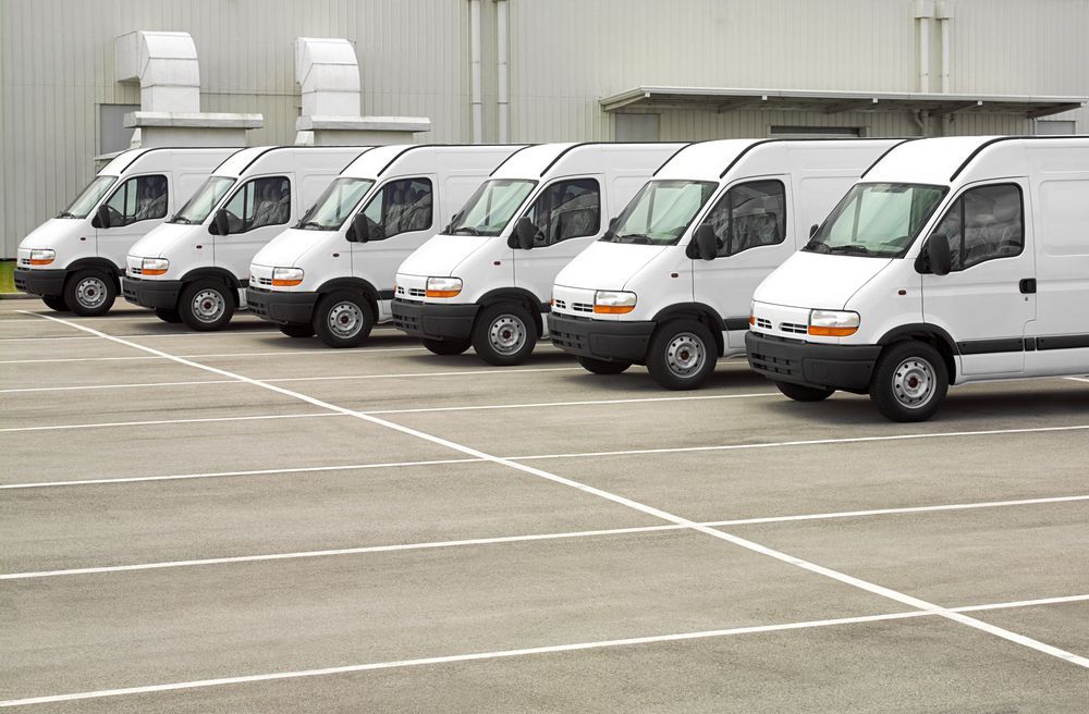 White Delivery Vans Parked in a Row in a Paved Lot, Beside a Building — Mission Truck Training in Maroochydore, QLD