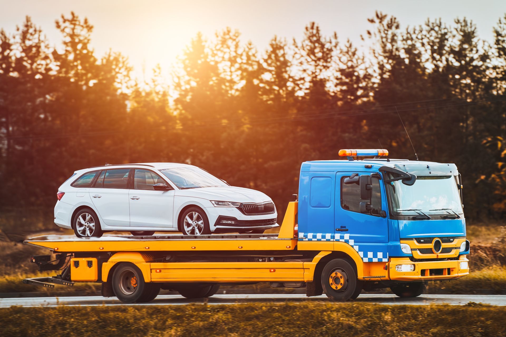 White Car on a Blue and Yellow Tow Truck, Driving on a Road — Mission Truck Training in Caboolture, QLD